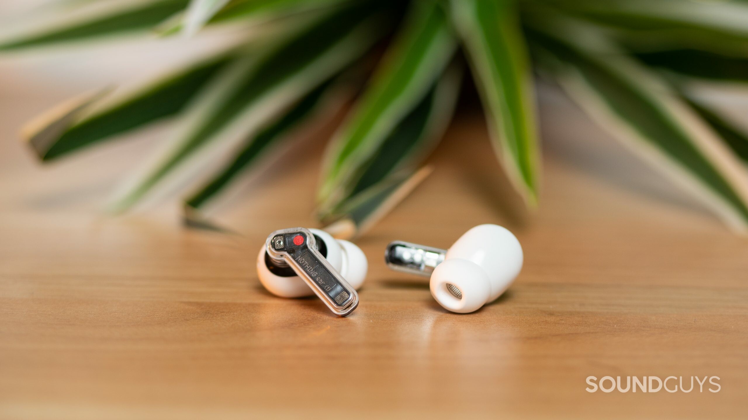 The Nothing Ear 1 earbuds lie flat on a wood table.