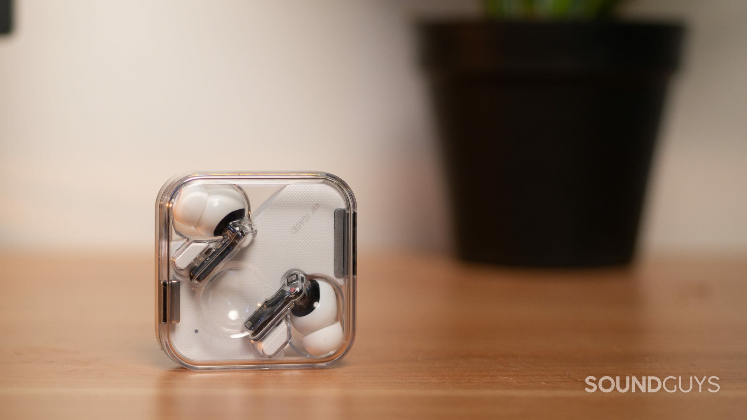 Nothing-Ear-1-in-case The Nothing Ear 1 true wireless earbuds rest in the clear case as it stands upright on a wood surface.