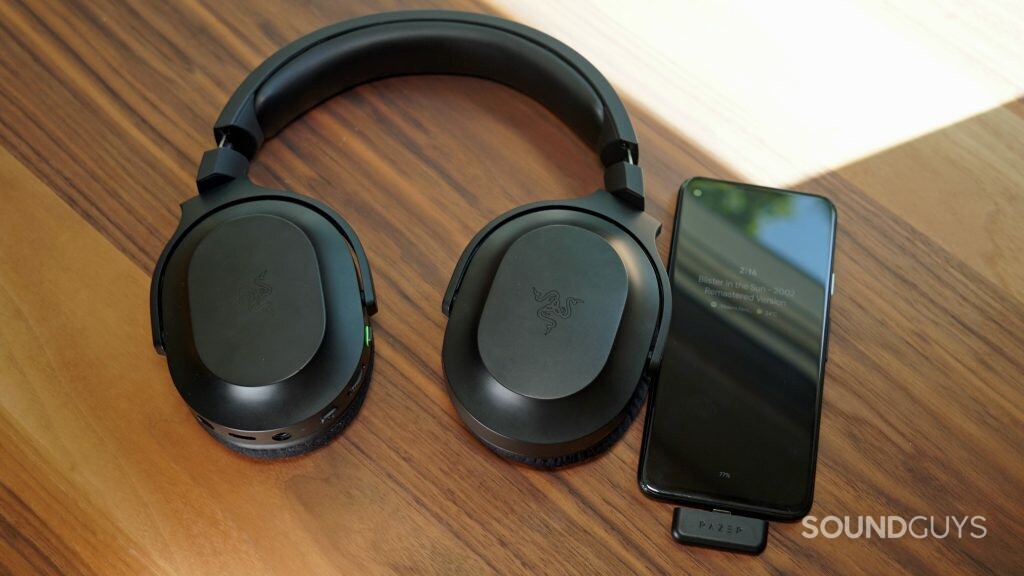 The Razer Barracuda X gaming headset lays flat on a table connected to a Google Pixel 4a via USB-C dongle.