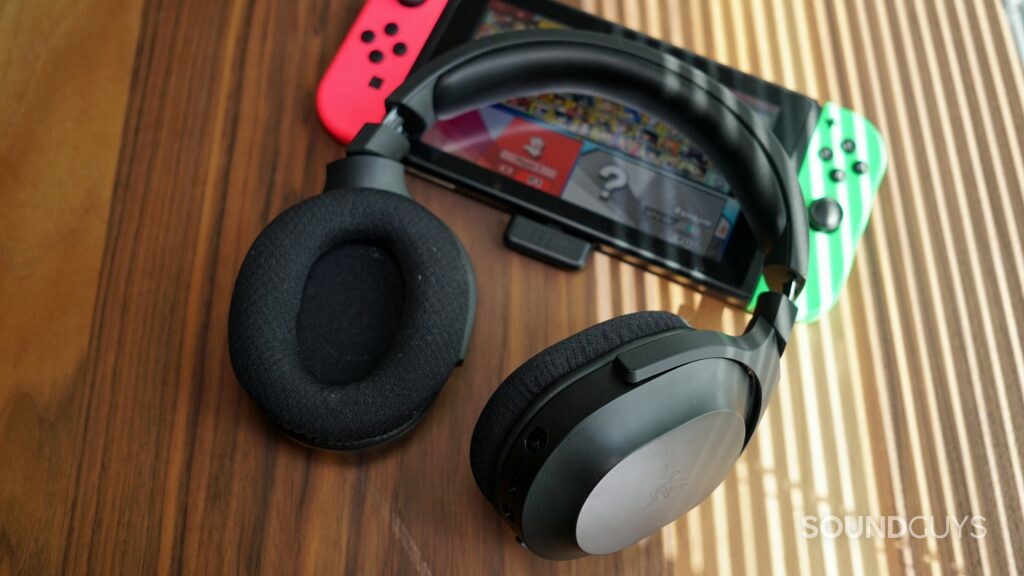 The Razer Barracuda X gaming headset leans on an undocked nintendo switch running Super Smash Bros. Ultimate.