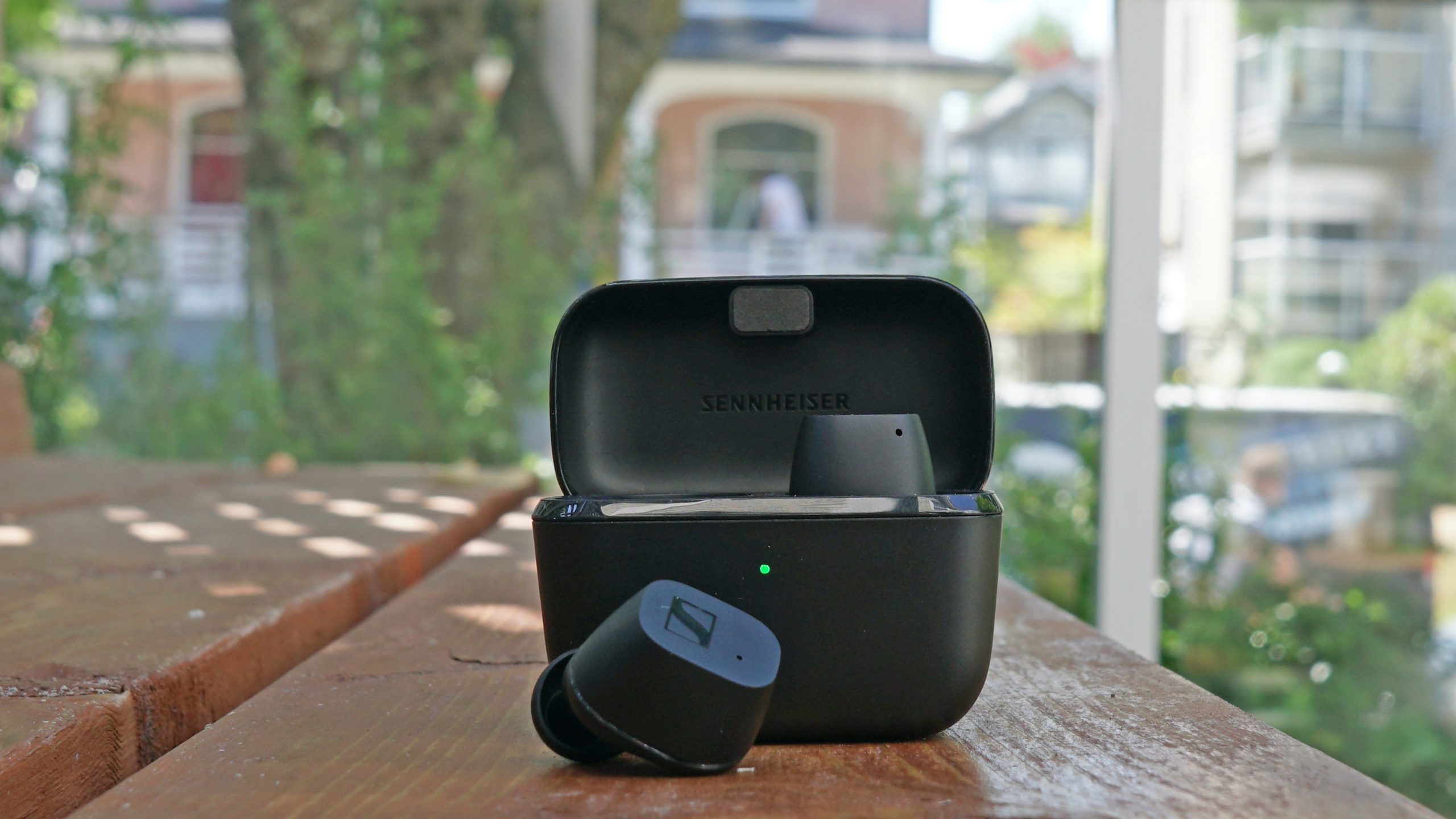 Picture of Sennheiser CX TWS earbuds with a case, placed on an outdoor table.