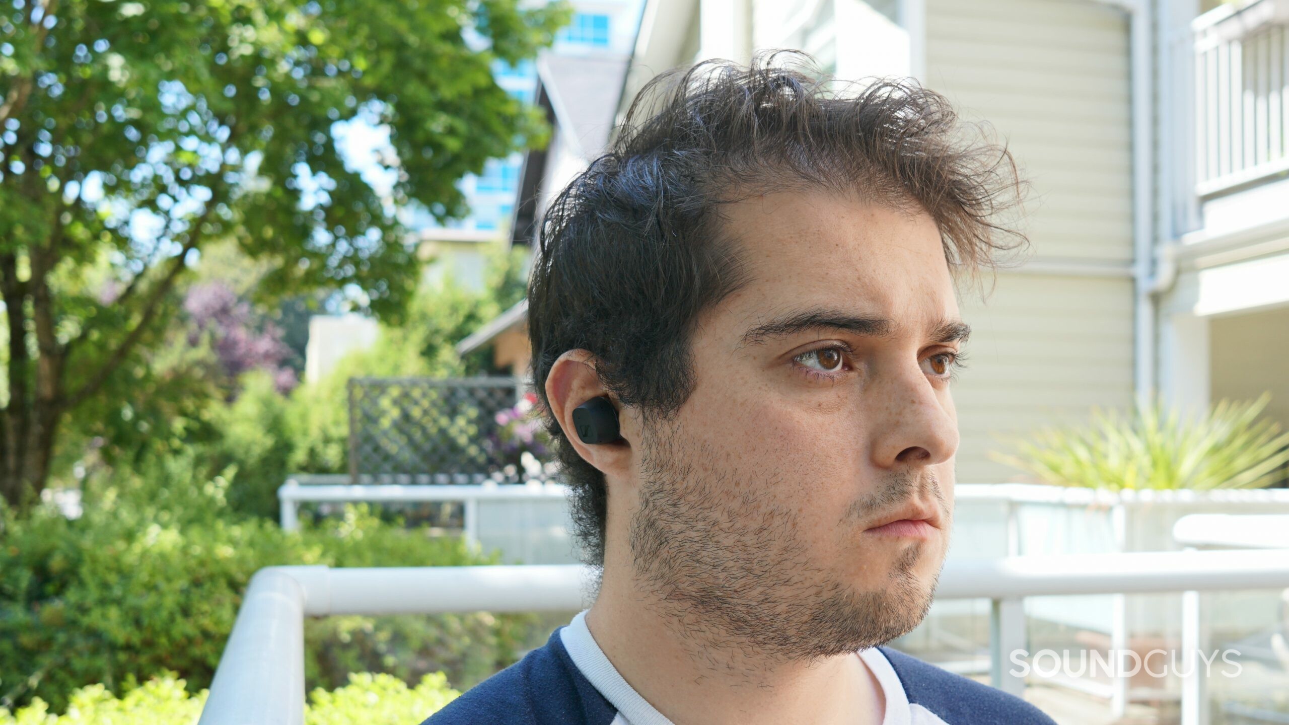 A man sits outside wearing the Sennheiser CX True Wireless earbuds.