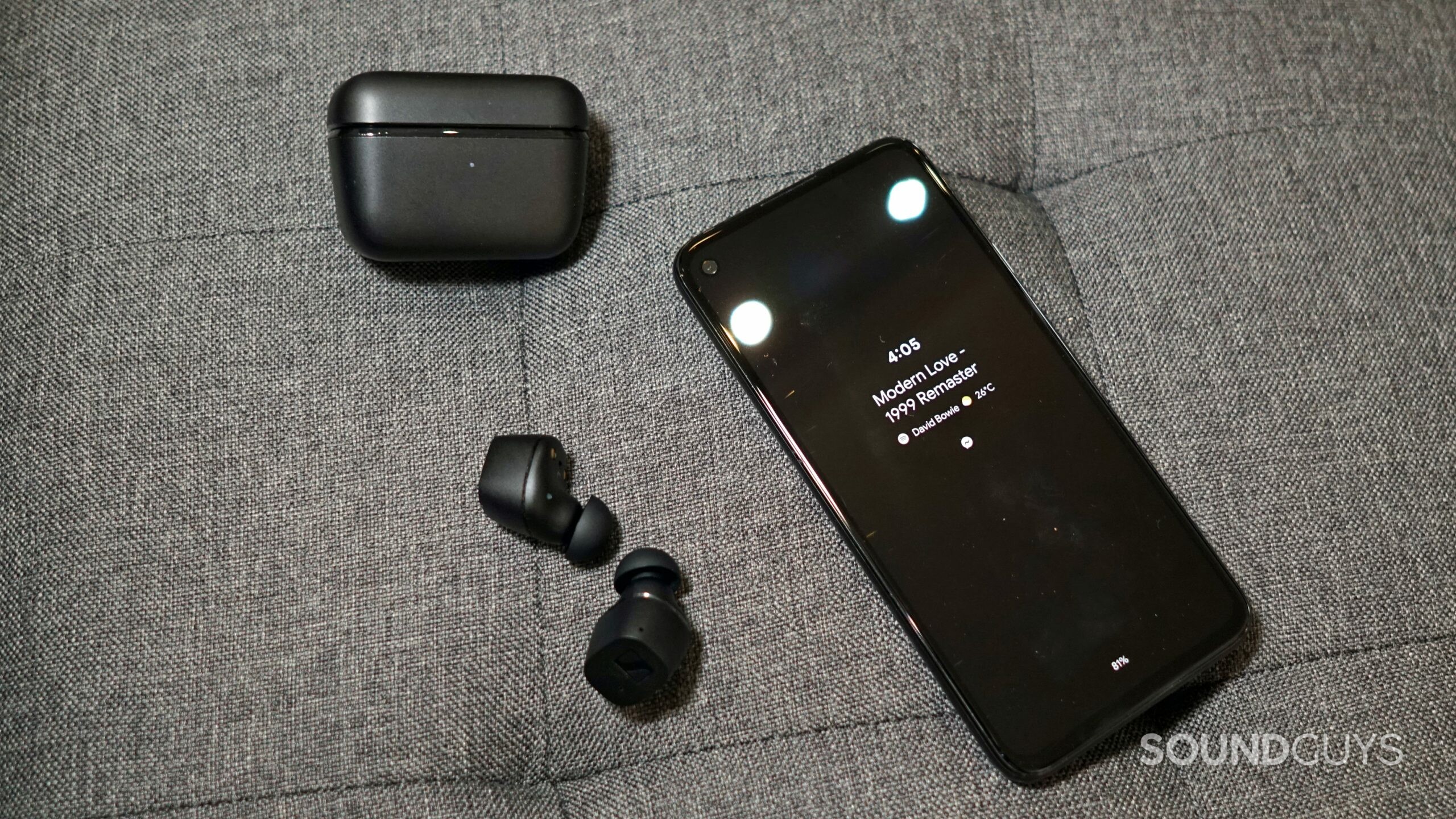Sennheiser-CX-TWS-phone-shot-Bowie The Sennheiser CX True Wireless lays on a fabric surface next to its charging case and a Google Pixel 4a.