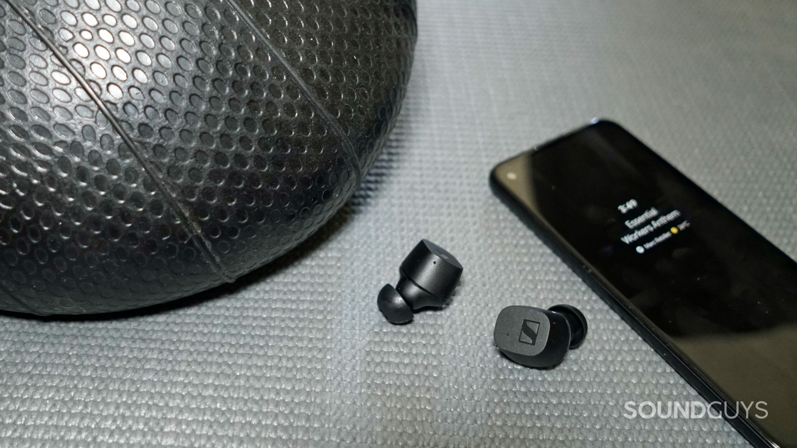The Sennheiser CX True Wireless lays on a workout mat next to a medicine ball and a Google Pixel 4a.