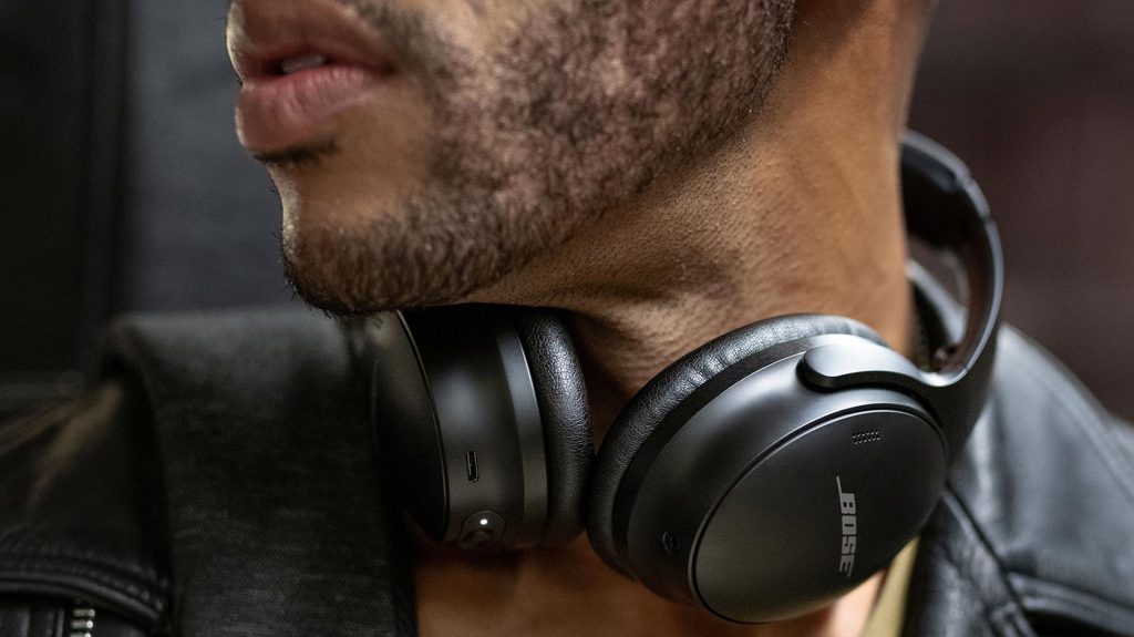A man wears the Bose QuietComfort 45 noise cancelling headphones around his neck.