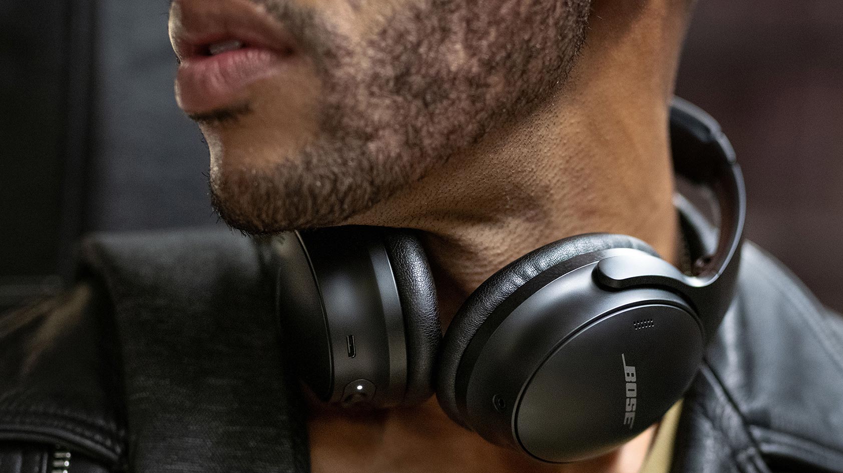 A man wears the Bose QuietComfort 45 noise canceling headphones around his neck.