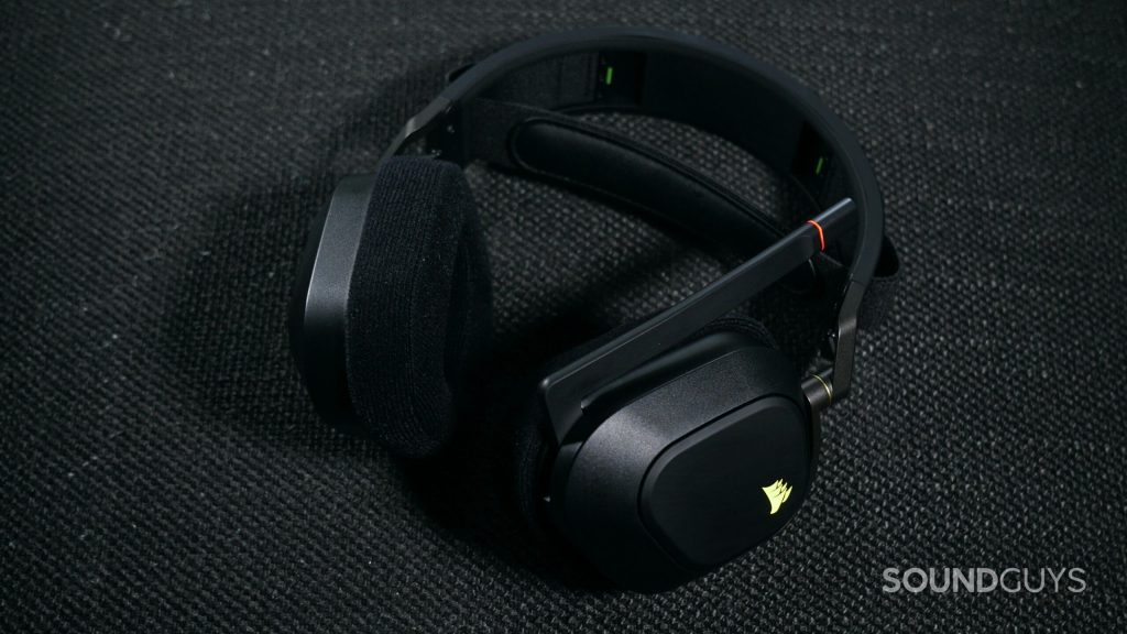 The Corsair HS80 RGB Wireless lays on a fabric surface, with its microphone flipped up.