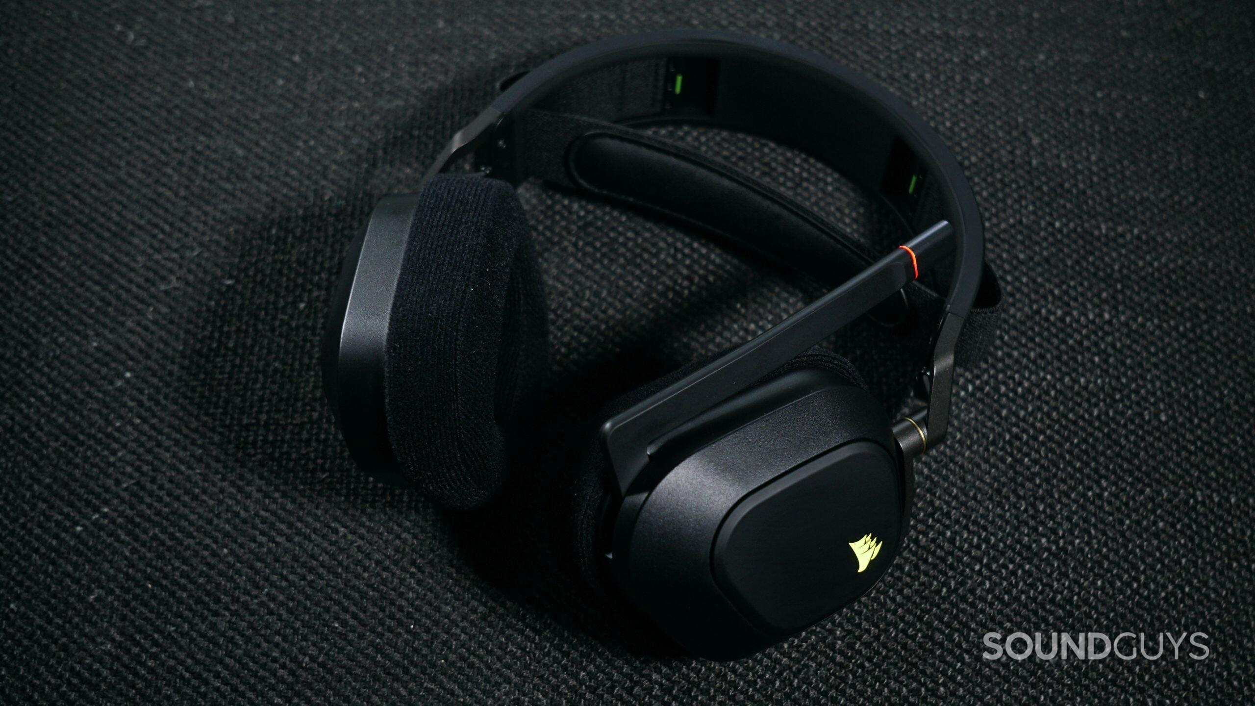 The Corsair HS80 RGB Wireless lays on a fabric surface, with its microphone flipped up.