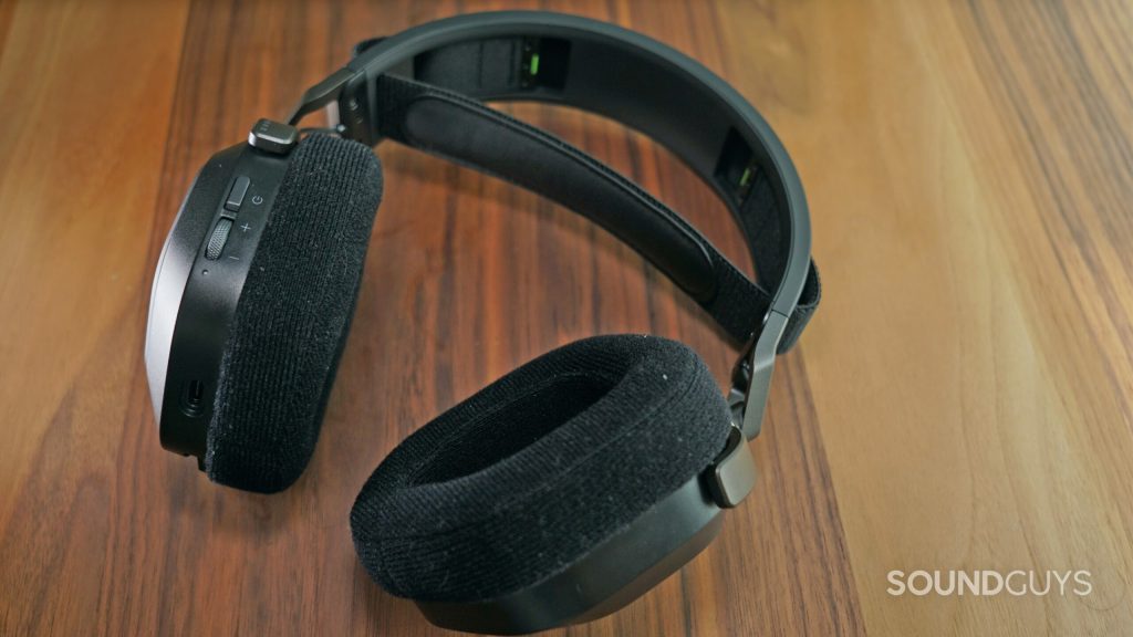 The Corsair HS80 RGB Wireless lays on a wooden table, with it's back facing up.