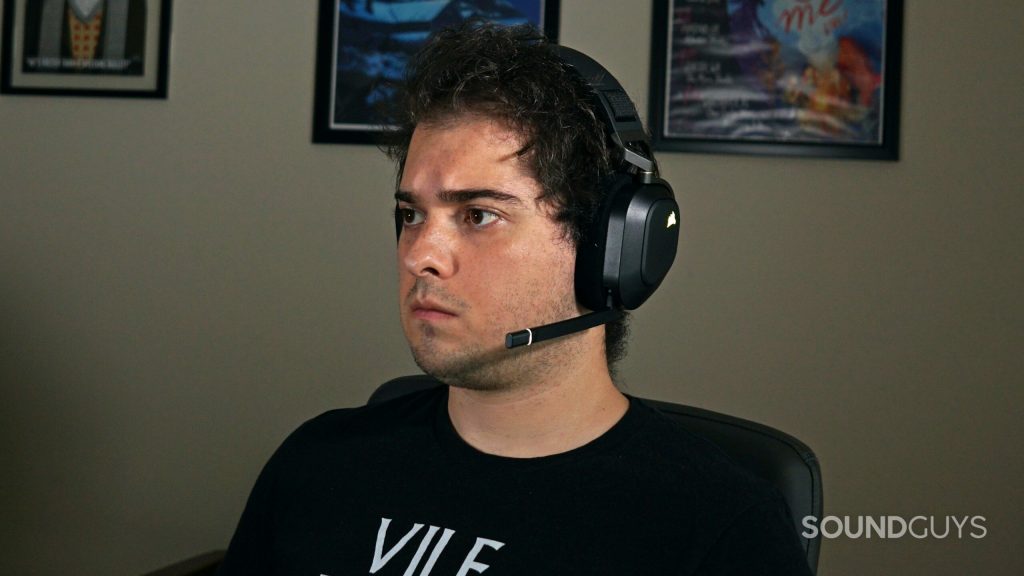 A man wears the Corsair HS80 RGB Wireless gaming headset sitting in a computer chair.