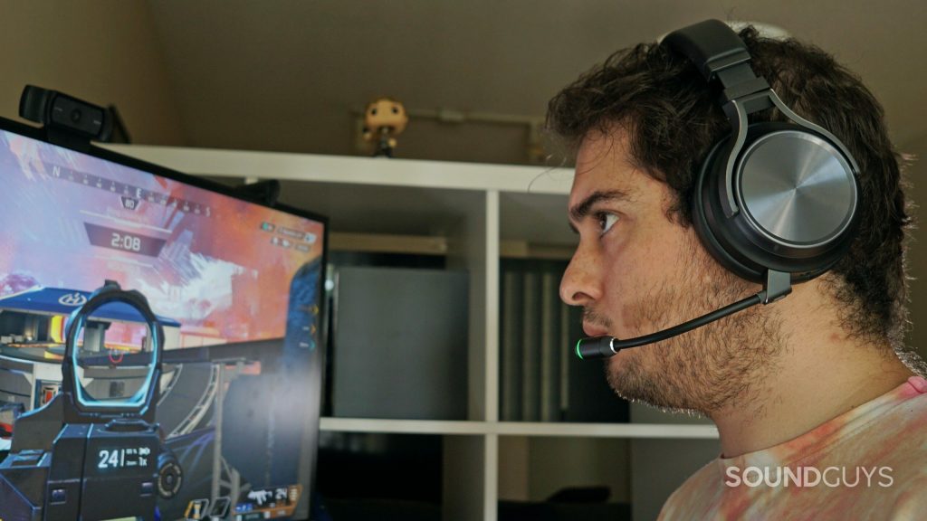 A man sits a computer playing Apex Legends wearing the Corsair Virtuoso RGB Wireless XT.