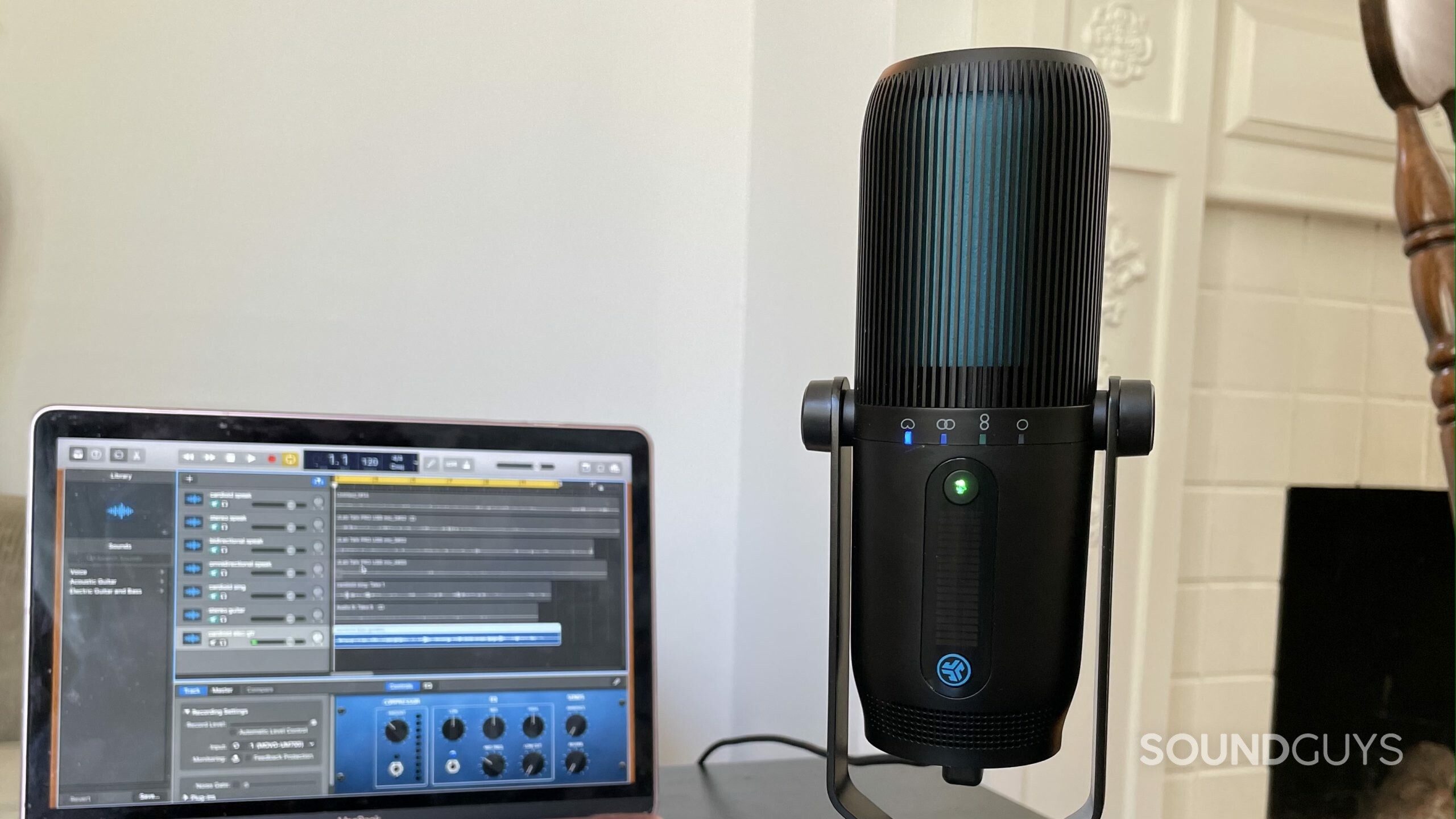JLab Talk PRO USB microphone on a table with a laptop with a DAW open in the background.