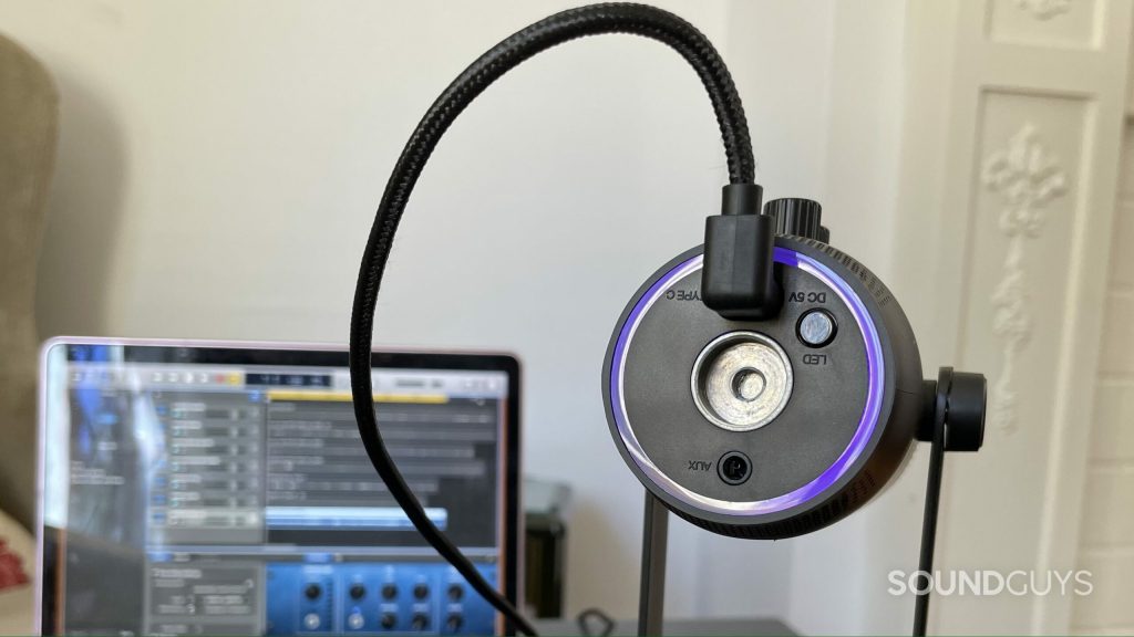 The underside of the JLab Talk PRO USB microphone with a laptop with a DAW open in the background.