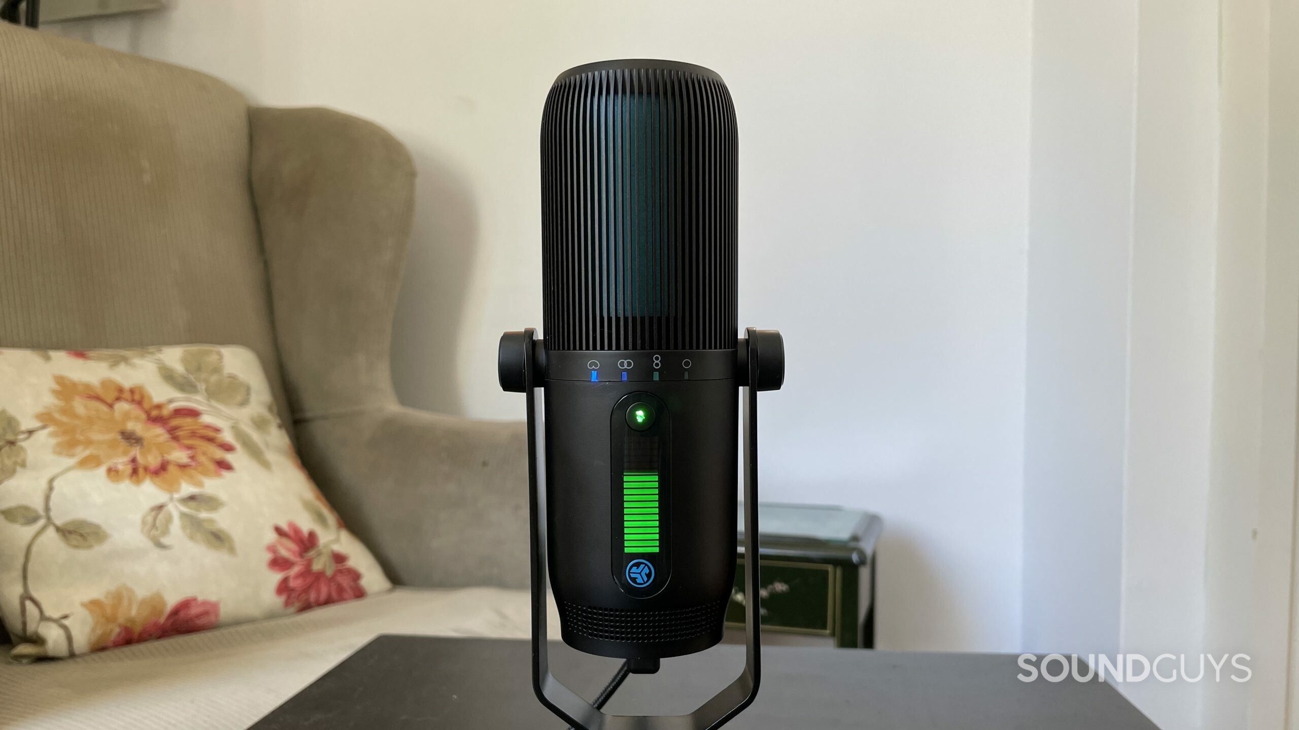 JLab Talk PRO USB microphone on a table with an armchair in the background.