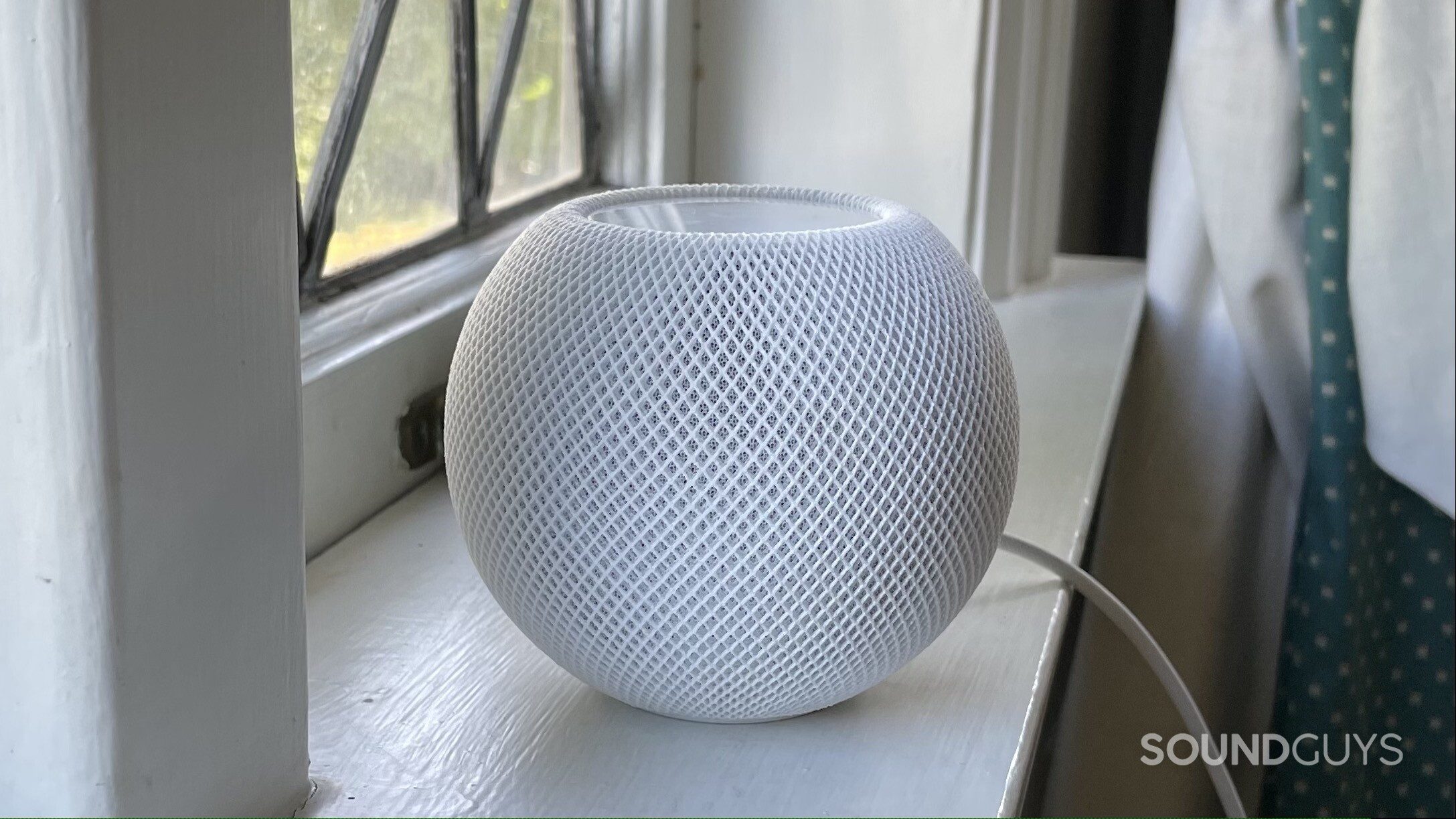 Apple HomePod mini sitting on a windowsill.