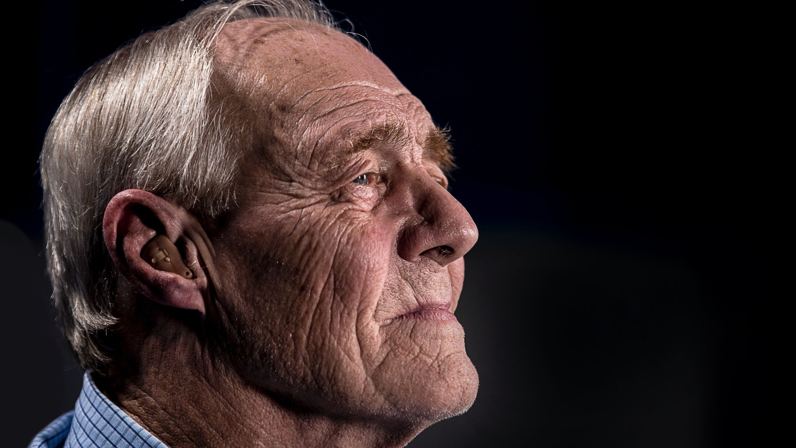 Elderly man with skin-colored ITE hearing aid.