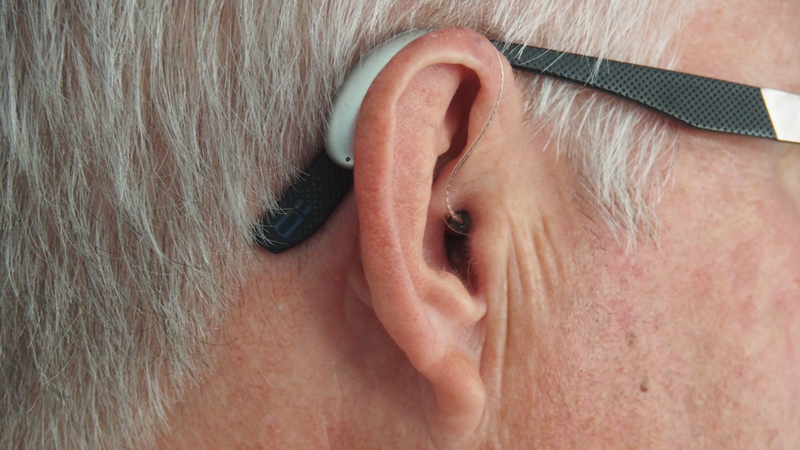 A man with glasses wearing a RIC hearing aid on his right ear.