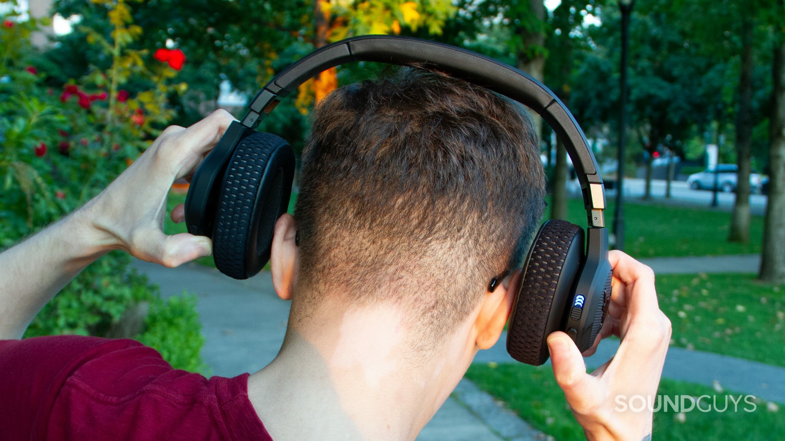 The back of Under Armour Project Rock by JBL headphones is shown being stretched out over the back of a man's head, about to put it on.