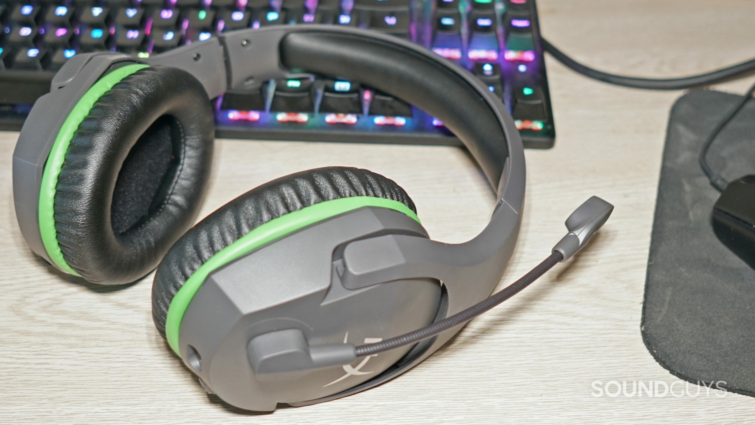 HyperX CloudX Stinger Core gaming headset lays on a desk next to a HyperX gaming keyboard and a Logitech gaming mouse.