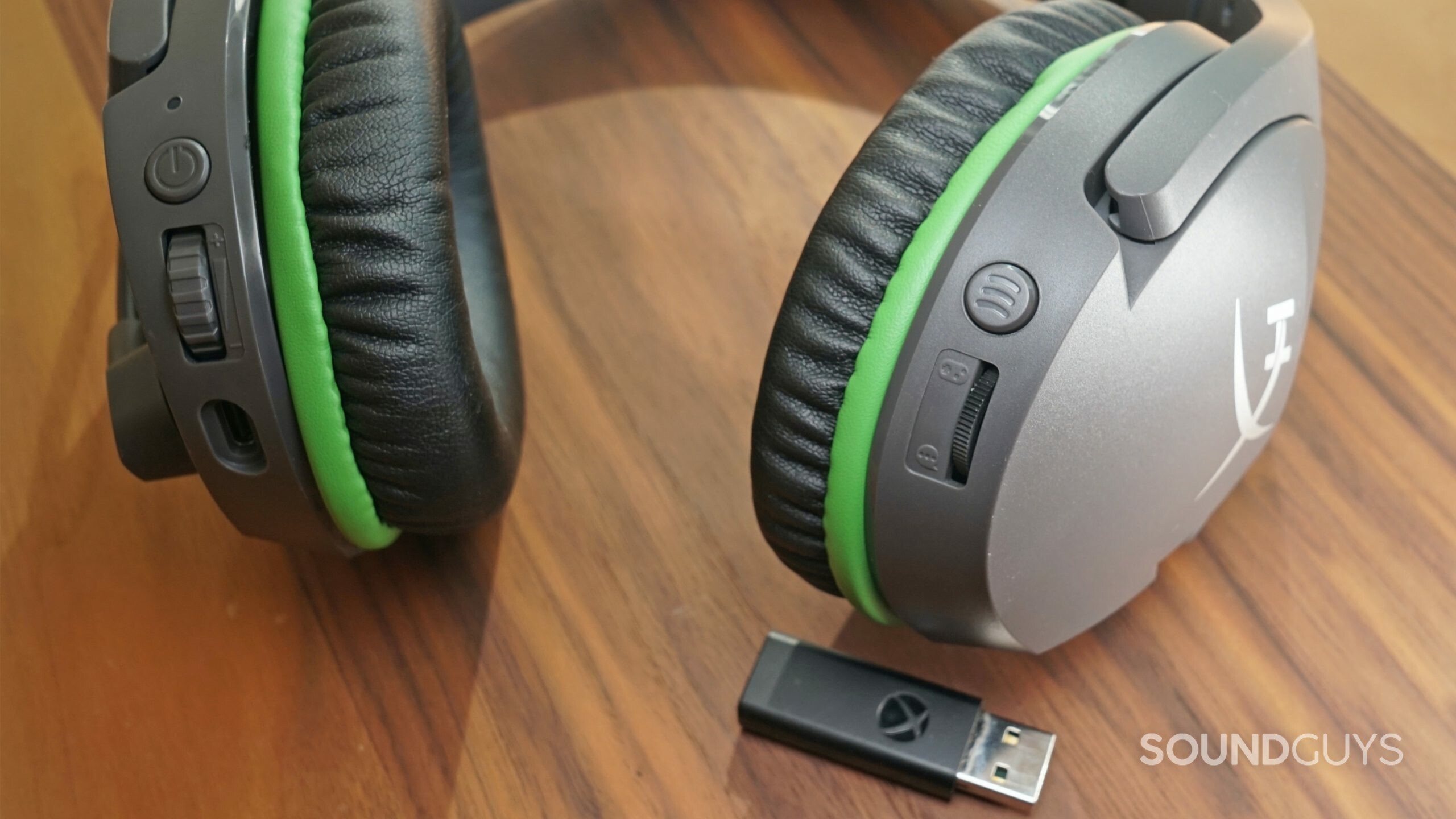 The HyperX CloudX Stinger Core lays on a wooden table next to an Xbox Wireless USB dongle