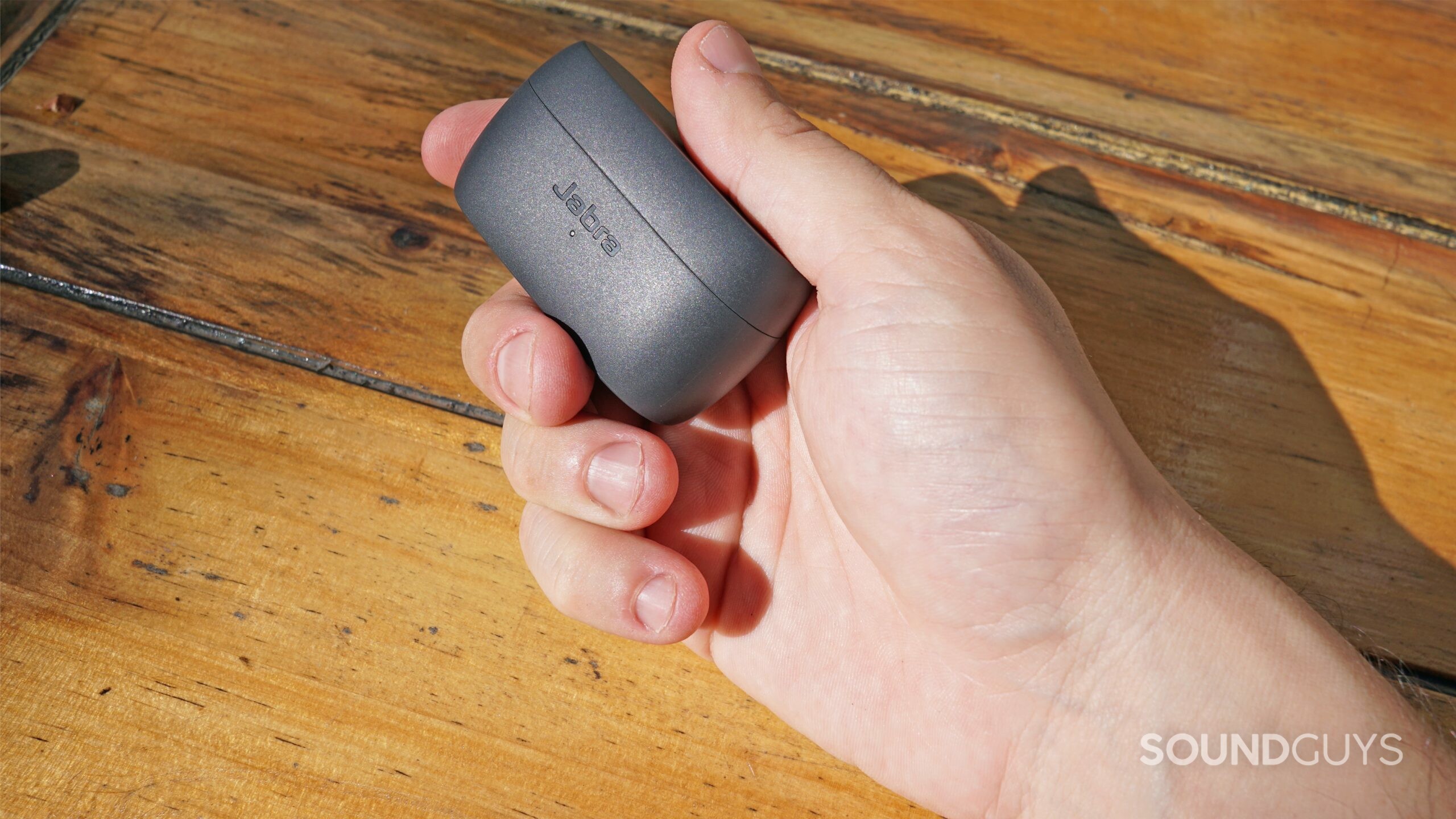 A hand holds the Jabra Elite 3 case outside.