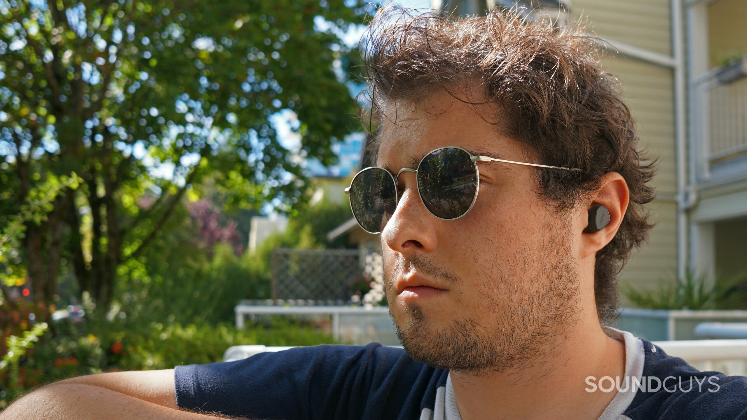 A man sits outside wearing the Jabra Elite 3.