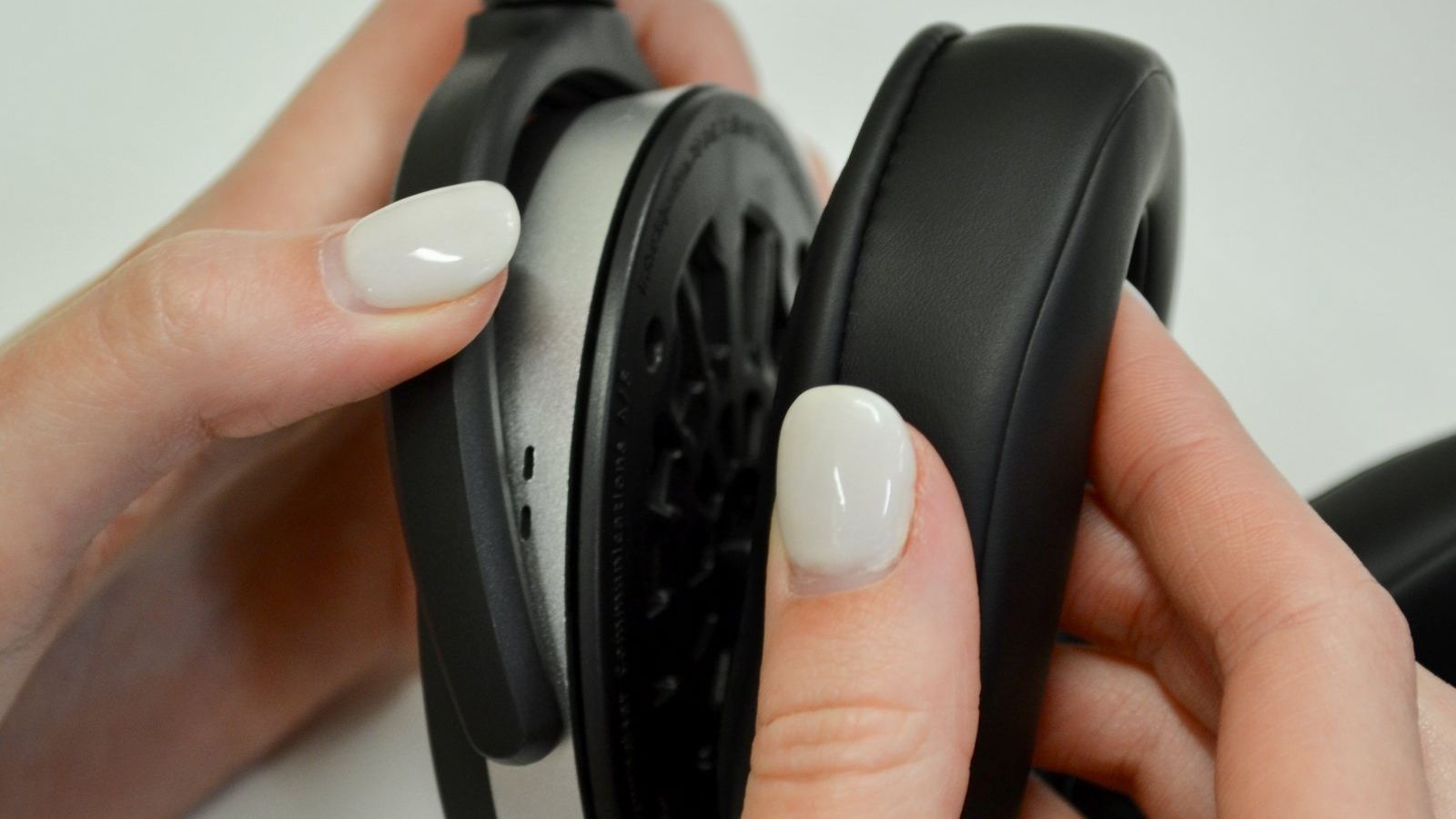 Woman removing ear pad from a pair of Sennheiser headphones.