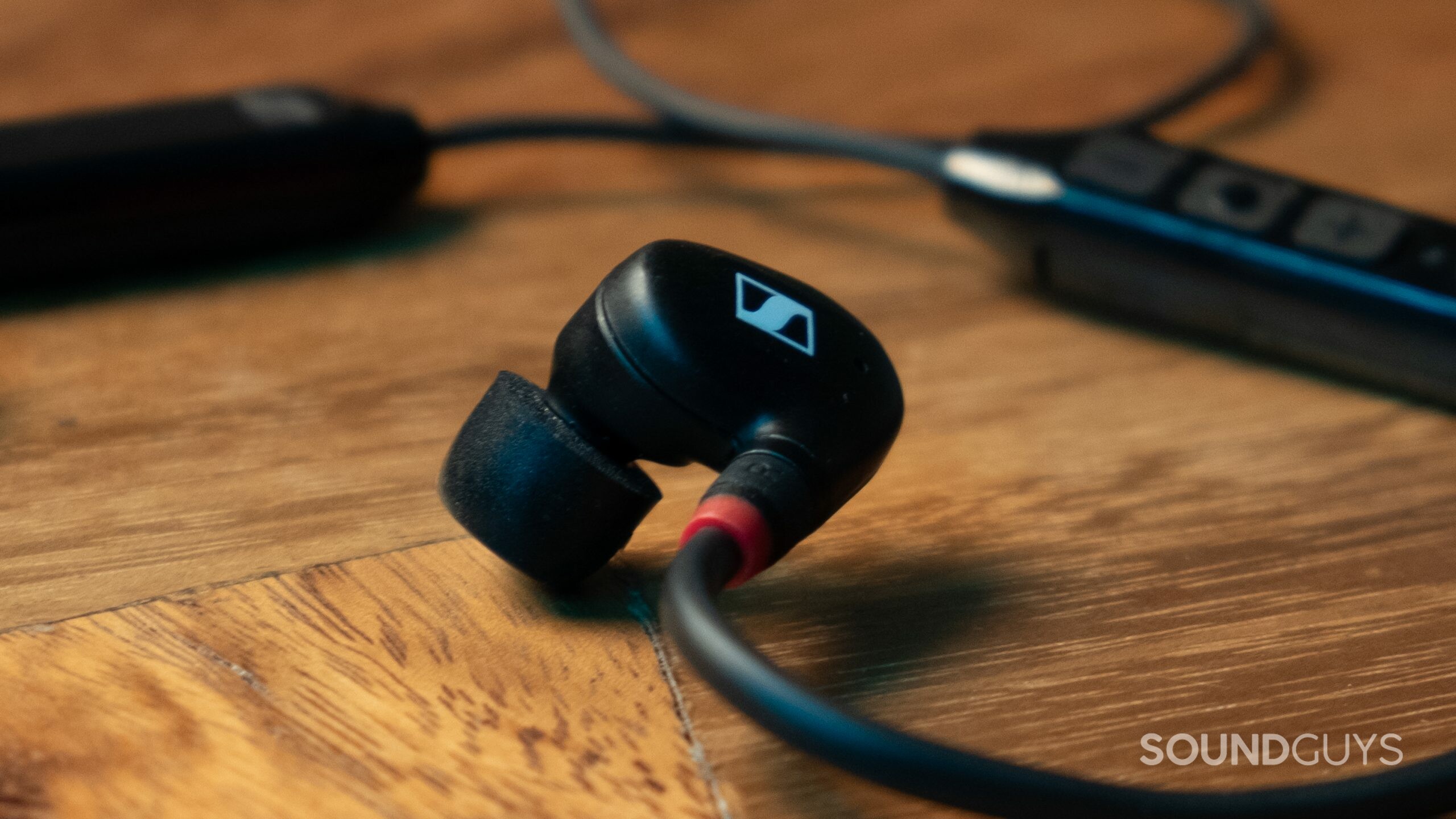 A close up of the Sennheiser IE 100 PRO Wireless earbud with the Bluetooth connector in the background.