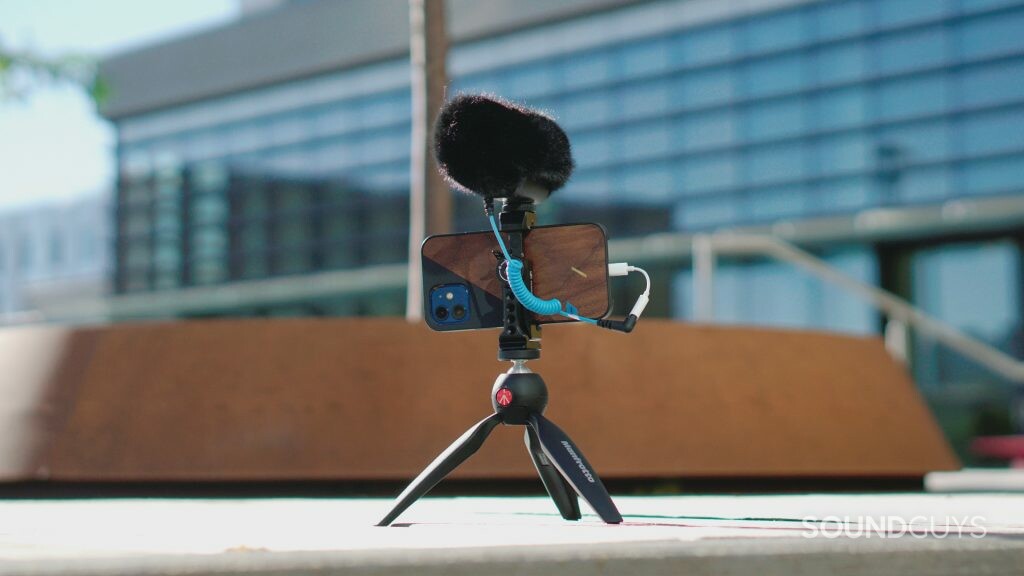 Sennheiser MKE 400 Mobile Kit mounted onto the included tripod on the ground in front of a glass building.