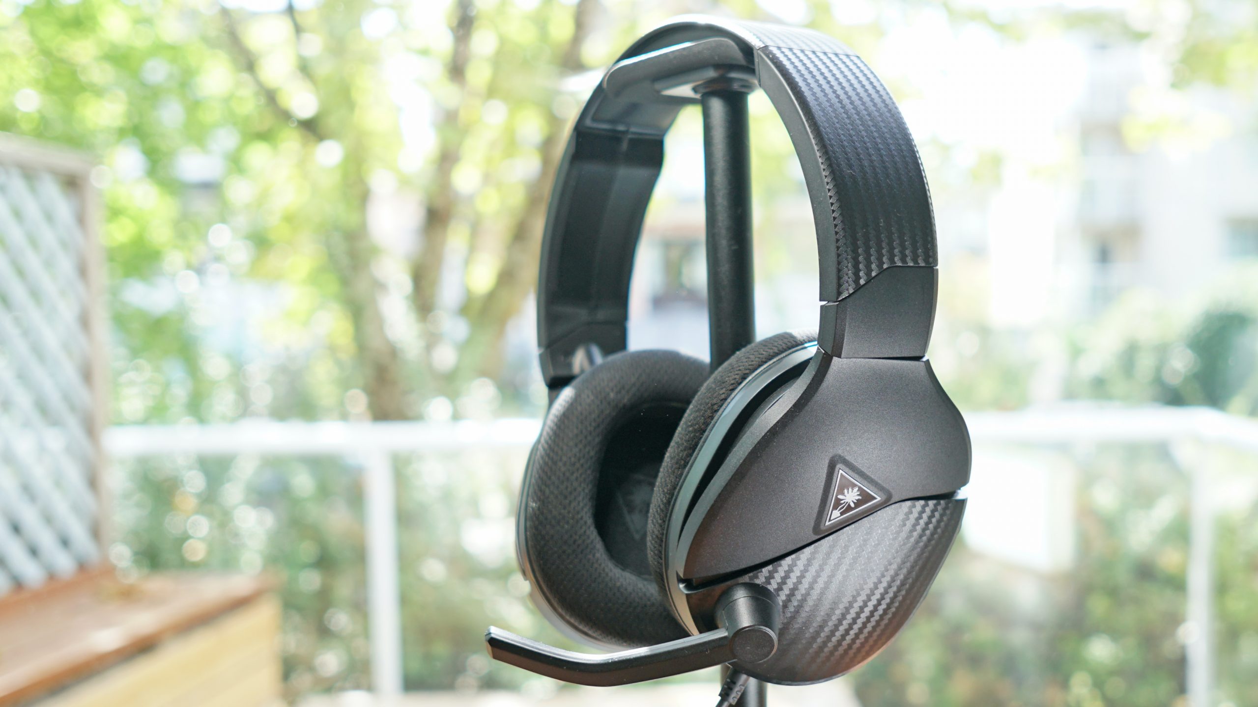 The Turtle beach Recon 200 Gen 2 sits on a headphone stand in front of a window.