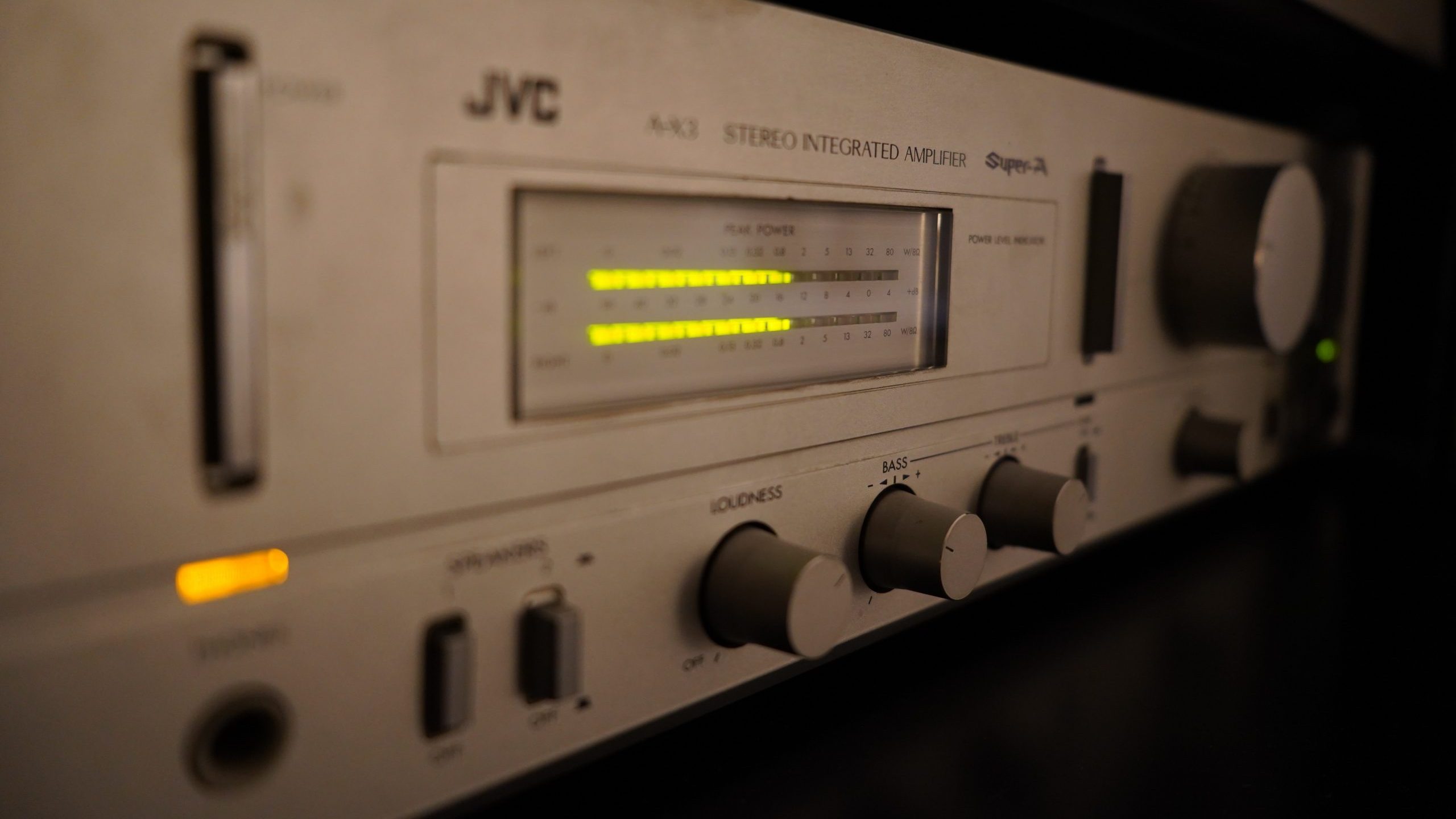 A JVC component hifi amplifier with power output displays illuminated.