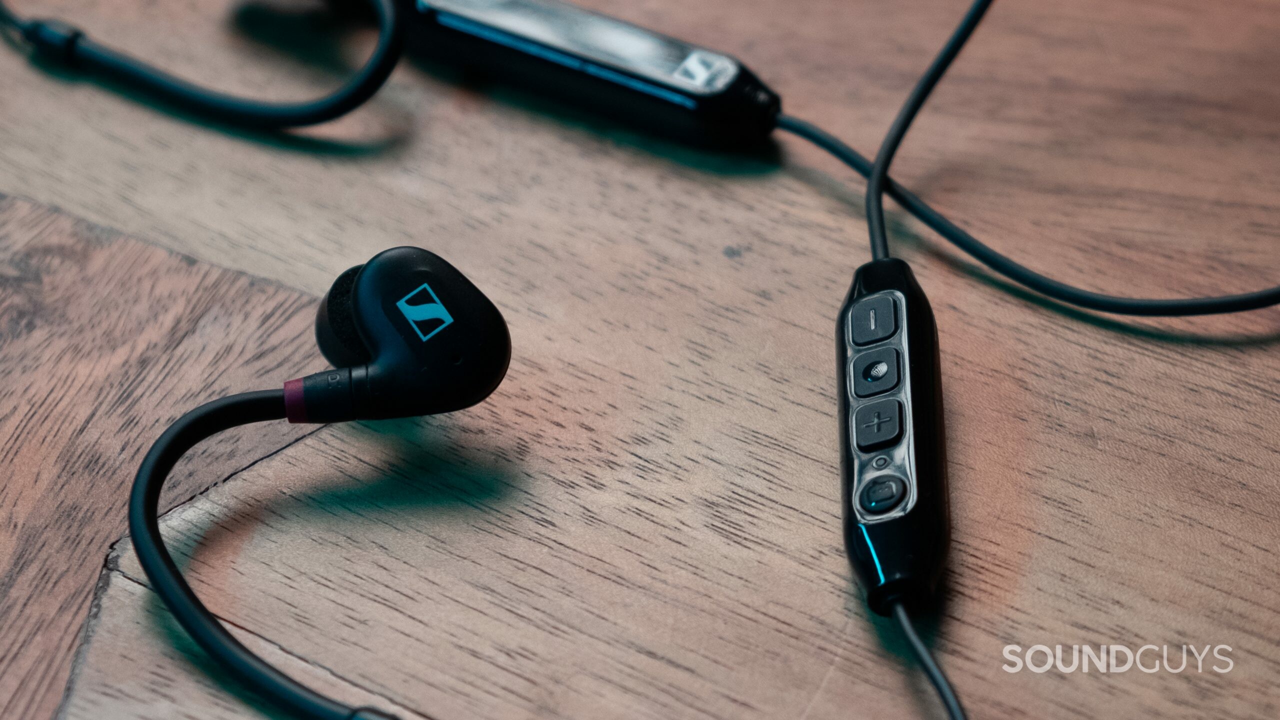 CLose up of the buttons on the Sennheiser IE 100 PRO Wireless BT Connector, shows a multi function button, volume, and pairing button. There's also the battery pack and a single earbud visible.