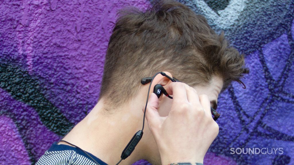 A man is showing how to angle the Sennheiser IE 100 PRO Wireless into his ear for a good fit.