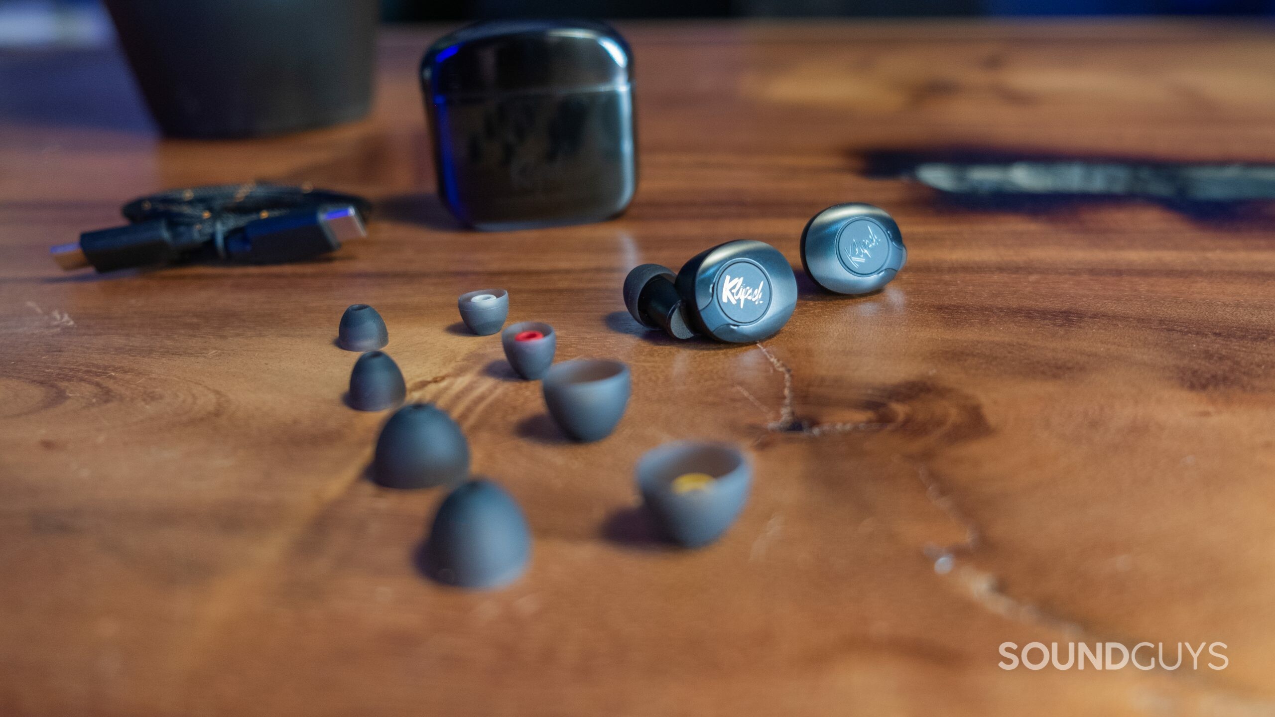 Earbuds, case, USB-C cable, case, and four spare ear tips sit on a wood surface of the Klipsch T5 II ANC.