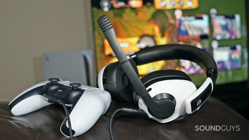 The EPOS H3 Hybrid sits on the arm of a couch plugged into a PlayStation DualSense controller, in front of