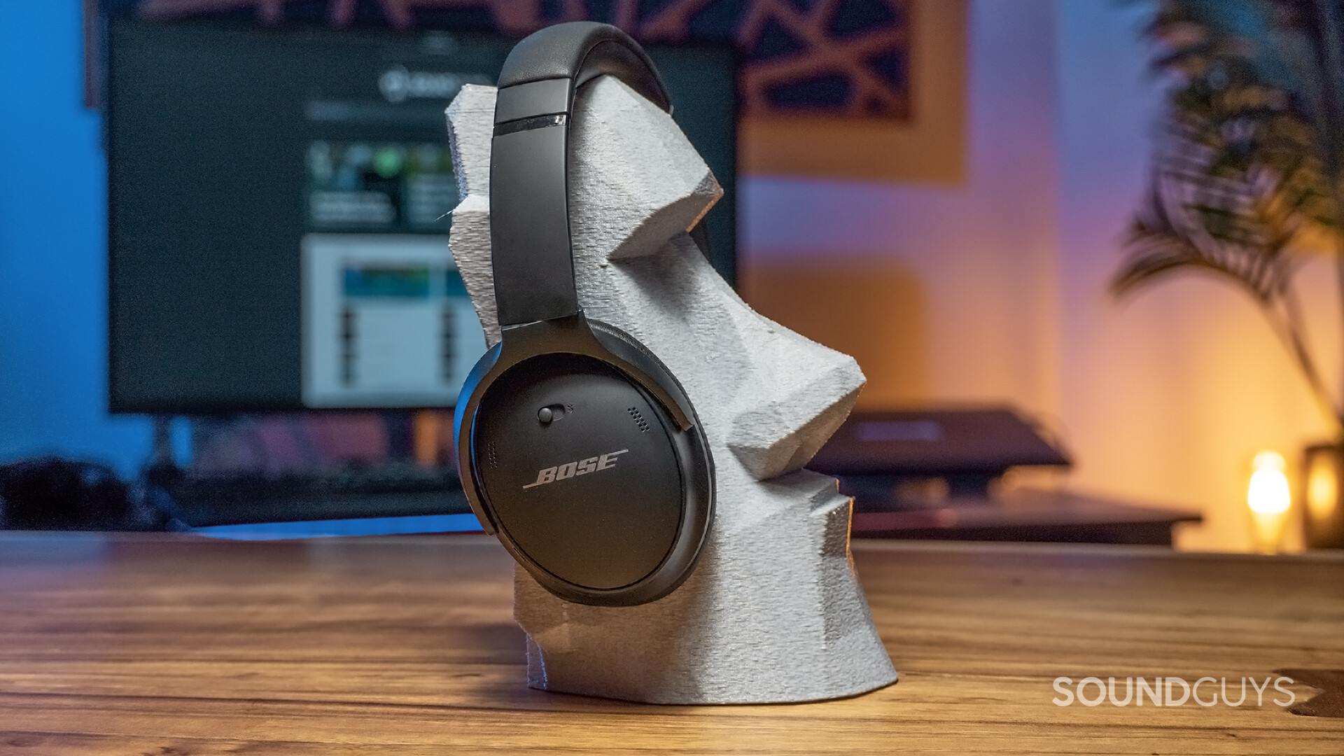 The Bose QuietComfort 45 sits on a easter island head-style headphone stand.
