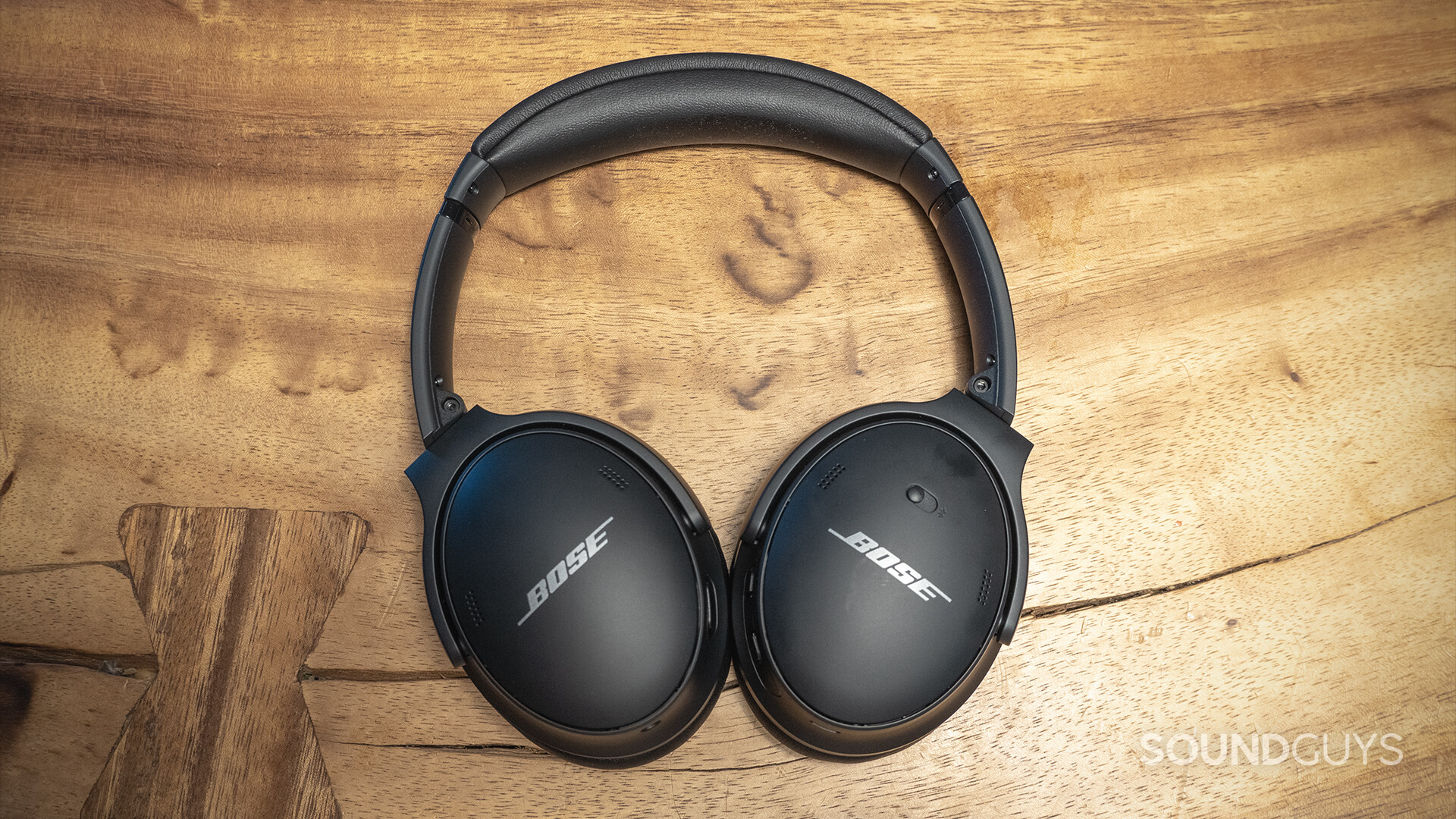 The Bose QuietComfort 45 noise canceling wireless headphones in black against a wooden surface.