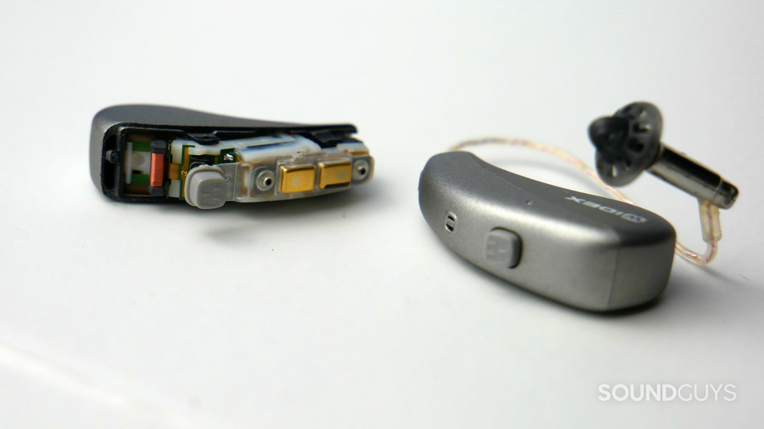 A pair of Widex MOMENT hearing aids with the left one disassembled to expose its telecoil.