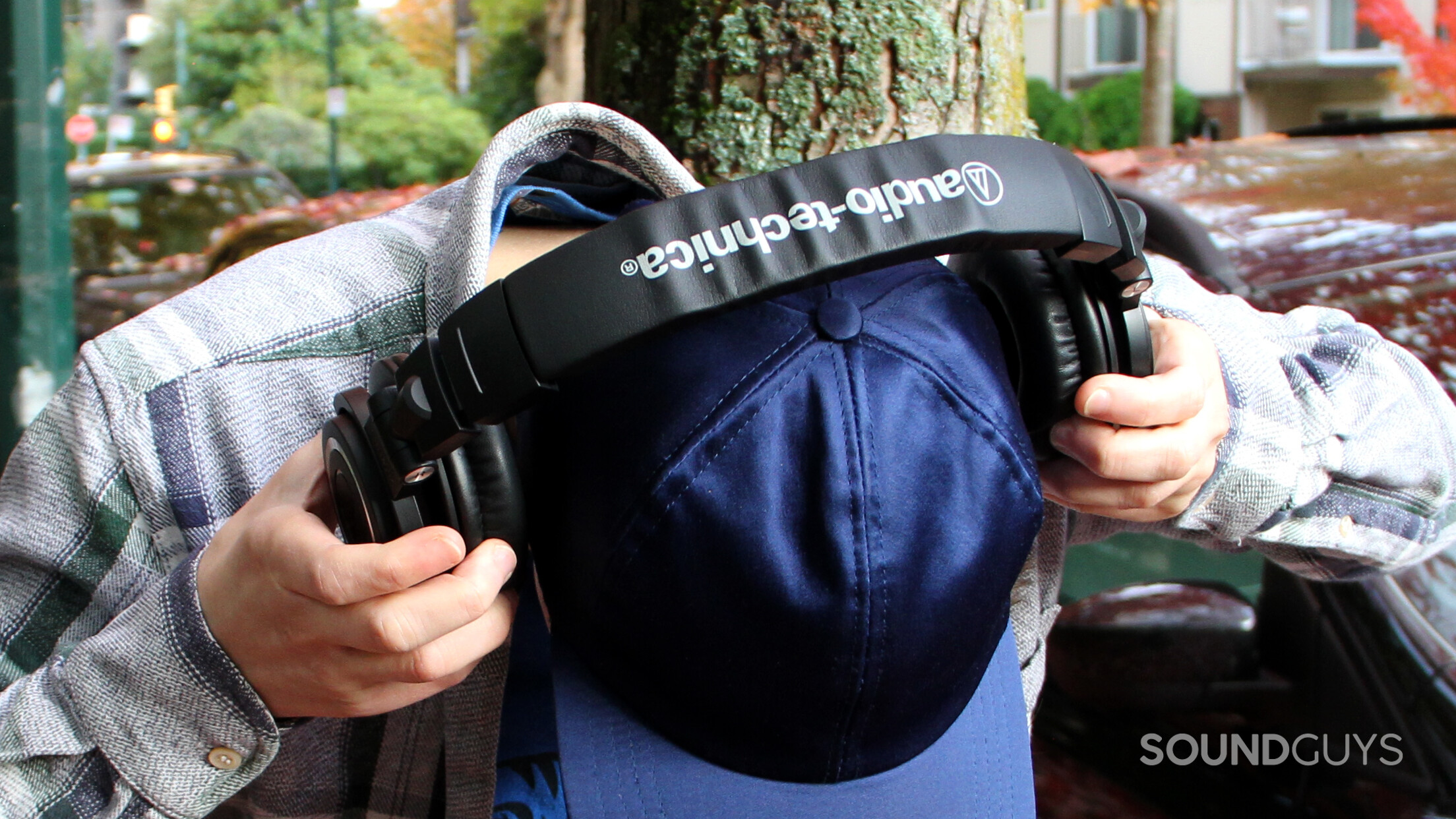 A man puts on the Audio-Technica ATH-M50xBT2, showing the top of the headphones.