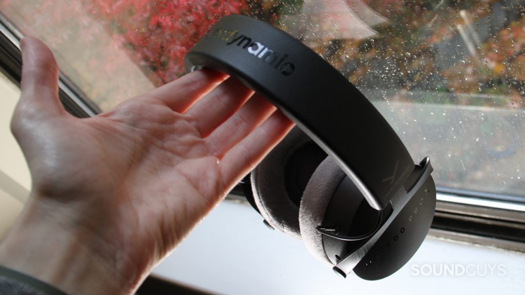 A man's hand holds the Beyerdynamic DT 700 Pro X by a window.