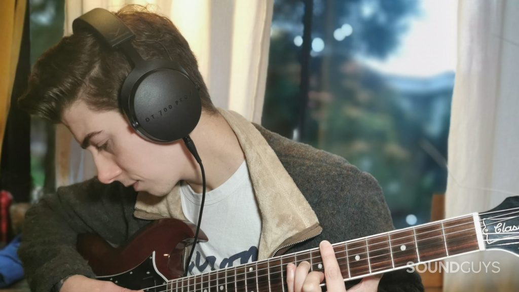 A man plays guitar wearing the Beyerdynamic DT 700 Pro X.