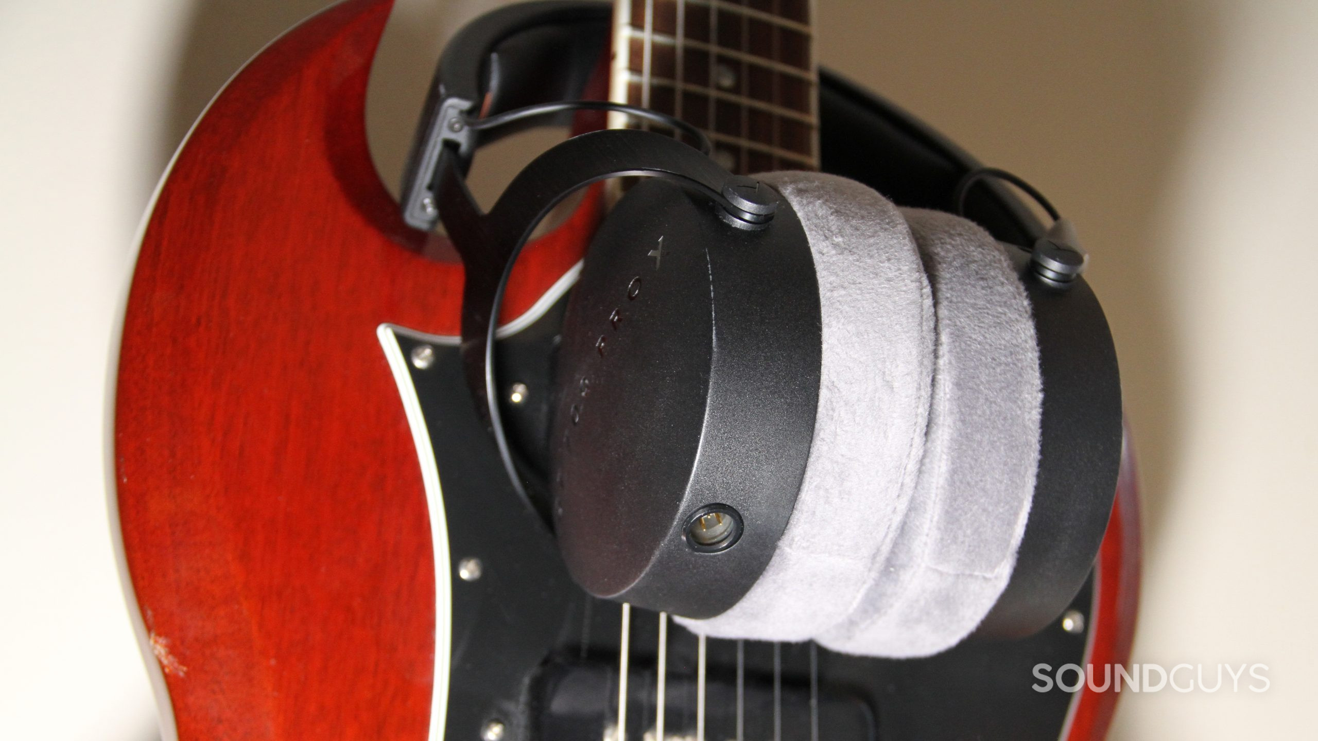 The Beyerdynamic DT 700 Pro X sits around the neck of a red guitar showing the cable connector.