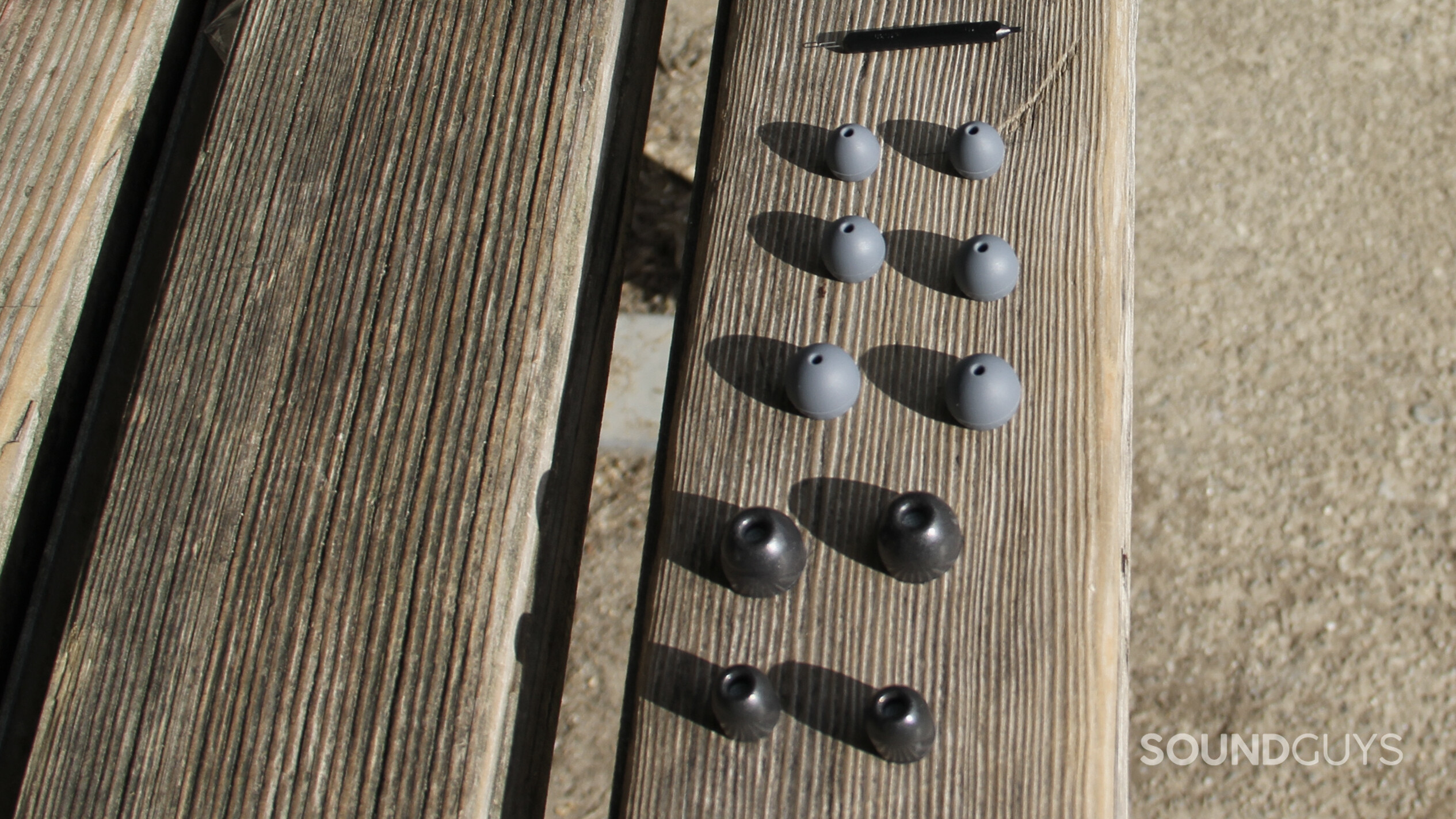 Five sets of ear tips and one cleaner included with the Shure AONIC 215 Gen 2 spread on a bench.