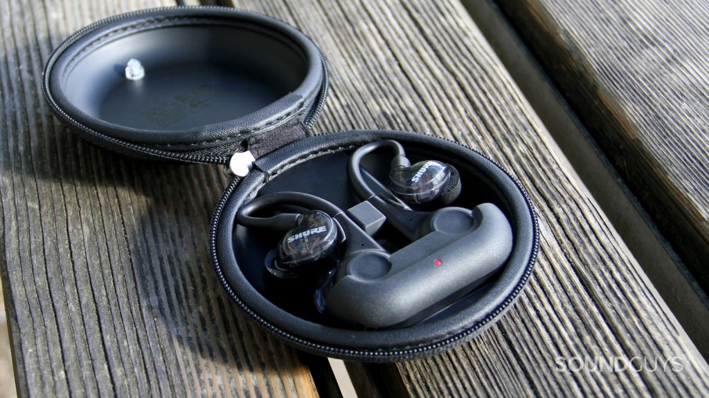 The SHure AONIC 215 Gen 2 sitting centered in its case on a wooden bench.
