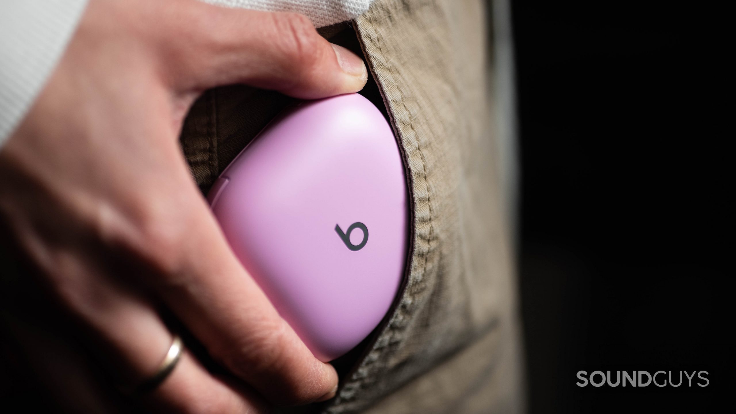A woman's hand pockets the Beats Fit Pro noise canceling true wireless earbuds case which is in the color purple.