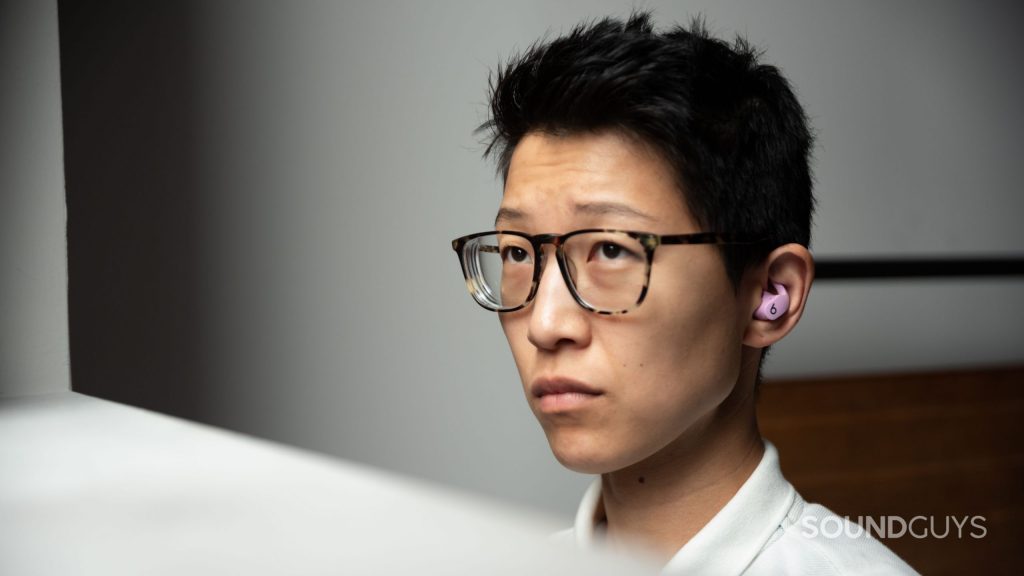 A woman wears the Beats Fit Pro noise canceling true wireless earbuds in purple.