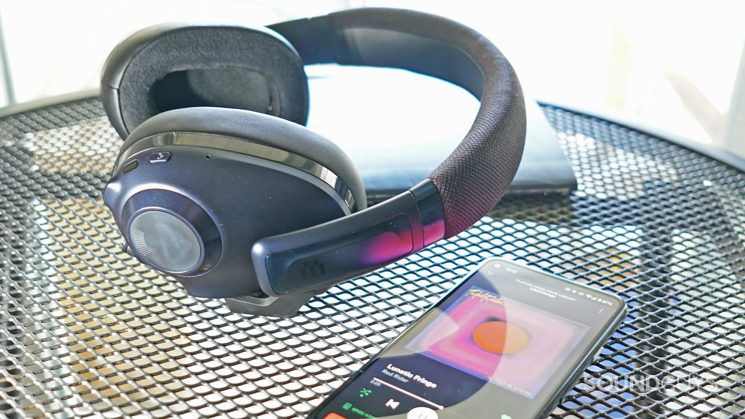 EPOS-H3PRO-Hybrid-Bluetooth-phone The EPOS H3PRO Hybrid lays on a metal table in front of a notebook, next to a Google Pixel 4a.