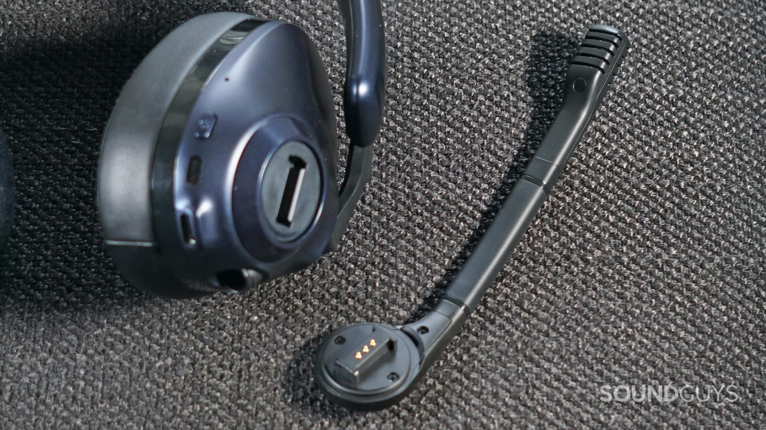 The EPOS H3PRO Hybrid gaming headset lays on a fabric surface with its microphone detached.