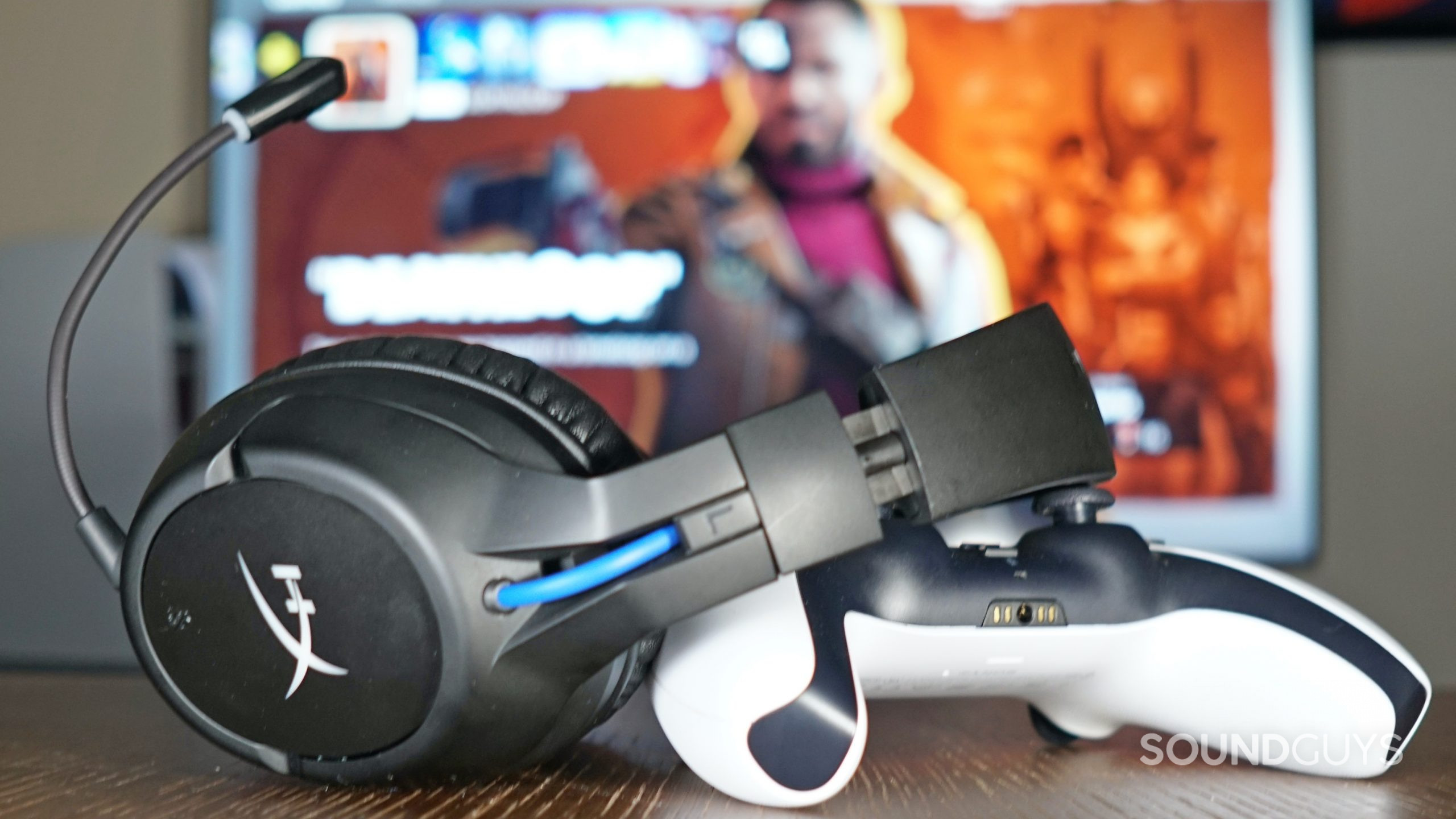 The HyperX Cloud Flight Wireless leans on a PlayStation DualSense controller in front of a TV displaying the PlayStation 5 home screen.