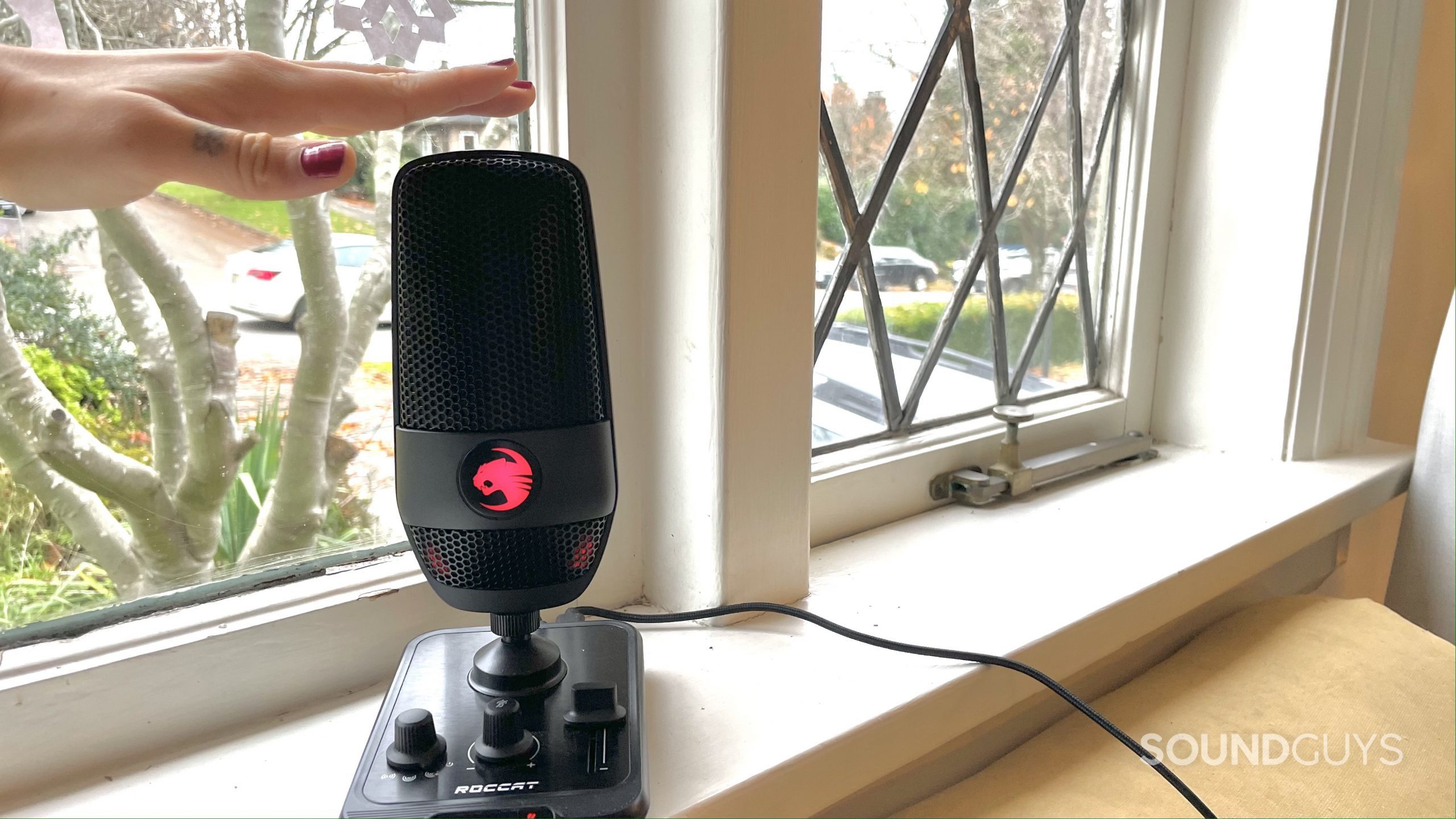 Roccat Torch red LED window A woman's hand hovering over the Roccat Torch which is on a windowsill.